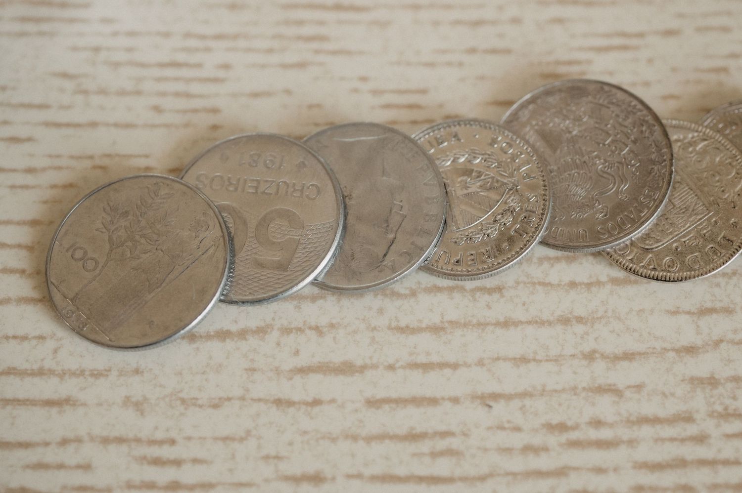 A row of vintage silver dimes arranged in a line on a light wooden surface.