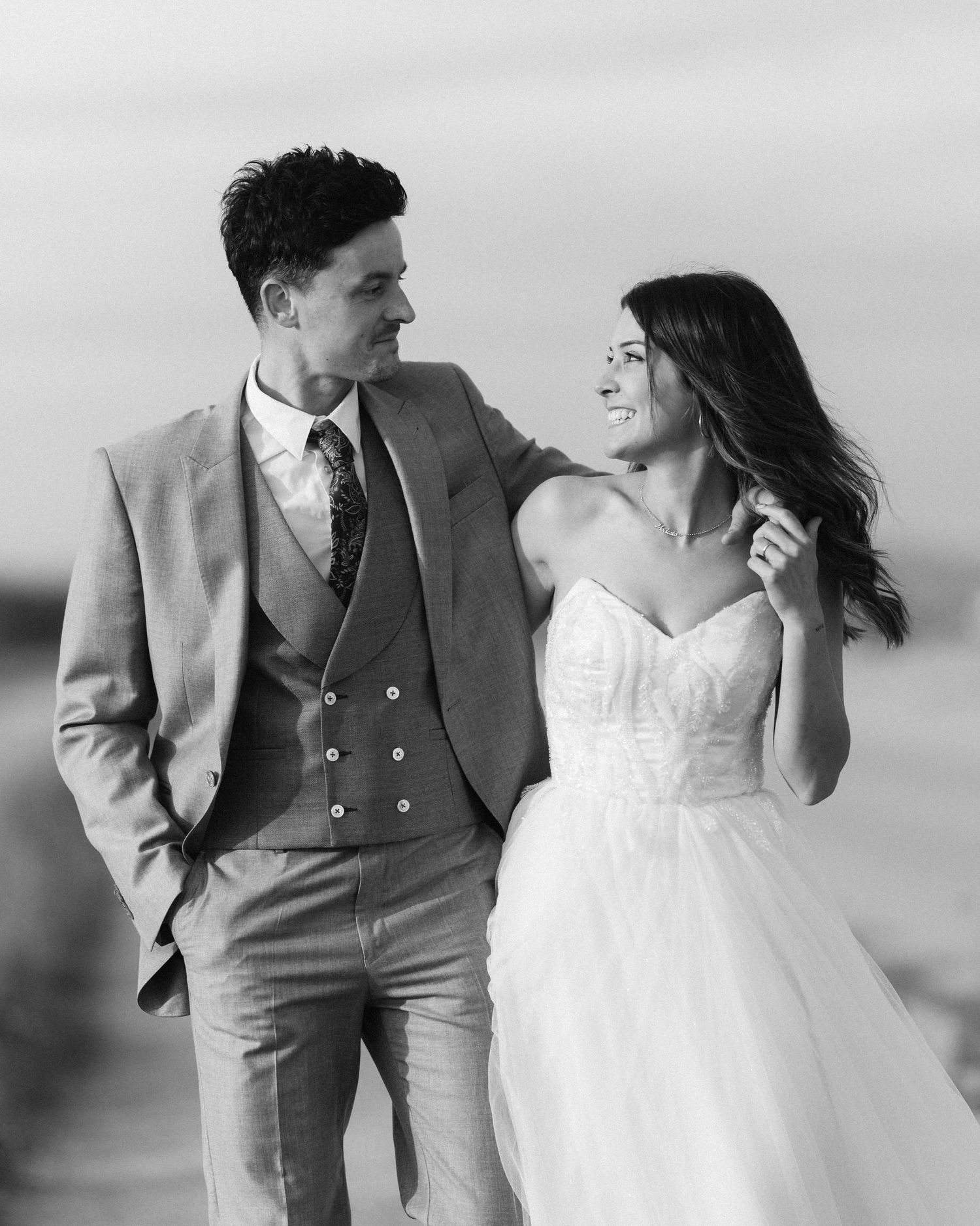 Bride and groom share a romantic glance in black and white wedding portrait outdoors.