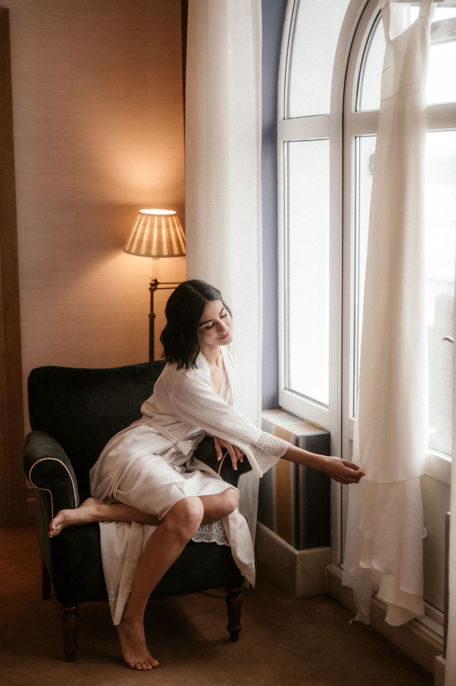 A series of artistic photos showing a person in white clothing reclining on a dark armchair near sunlit windows.