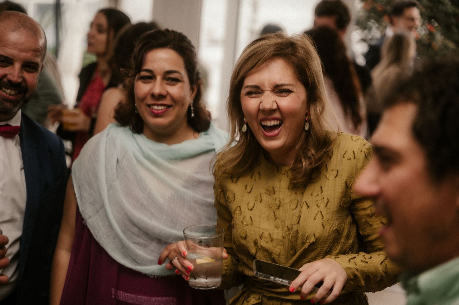 Party guests laugh and socialize during a festive celebration indoors.