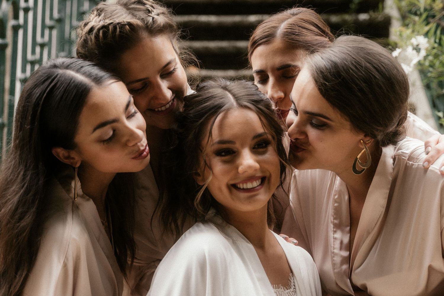 A group of friends in white robes smile and huddle together in an intimate moment.