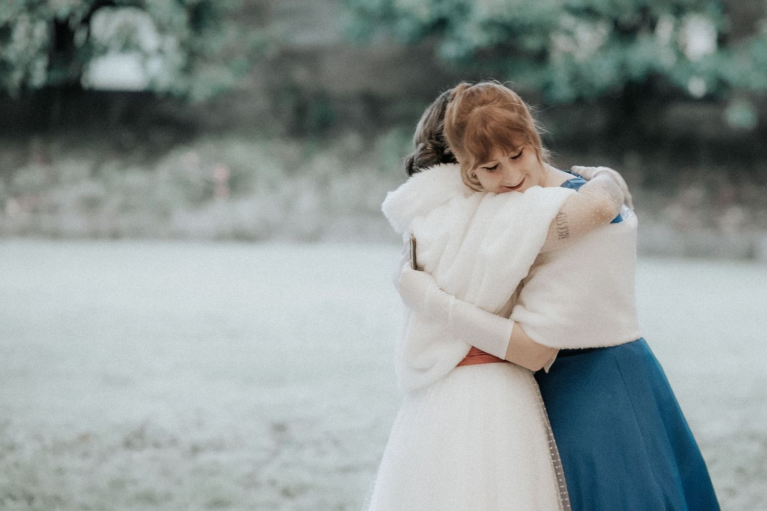 A romantic wedding couple embraces in a garden setting wearing white and navy blue attire.