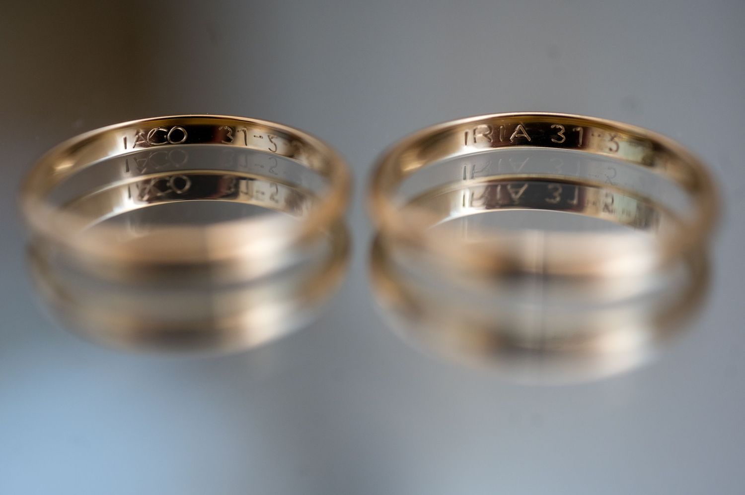 Close-up view of four identical gold wedding bands displayed side by side on a light surface.