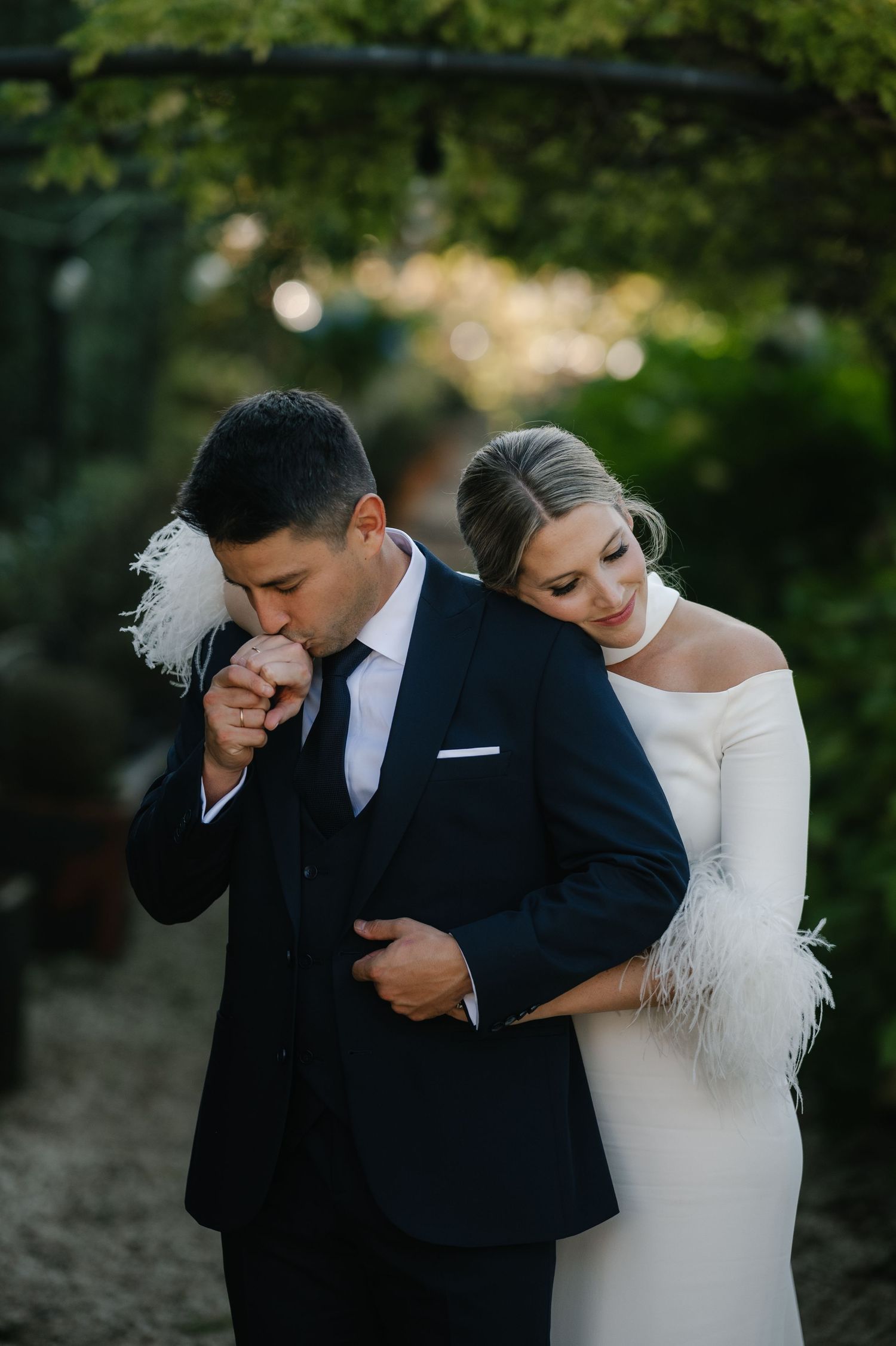 Intimate wedding couple portraits in an outdoor garden setting with elegant white dress and navy suit.