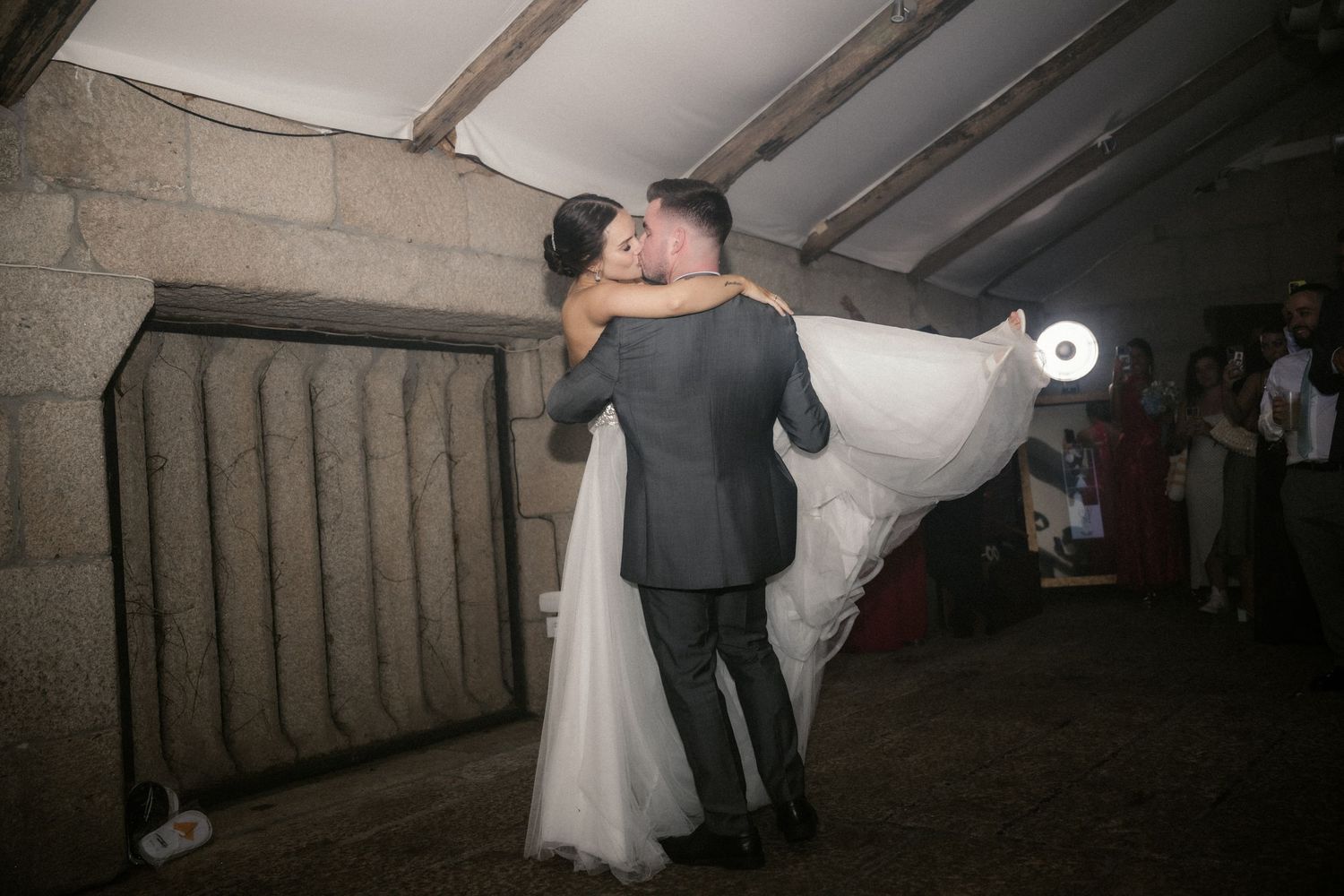 Couples dancing together at a dimly lit wedding reception venue with dramatic lighting effects.