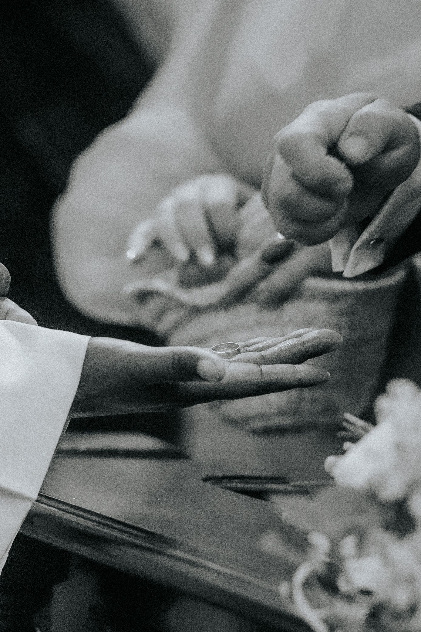 Black and white close-up of hands exchanging paper documents across a table surface.