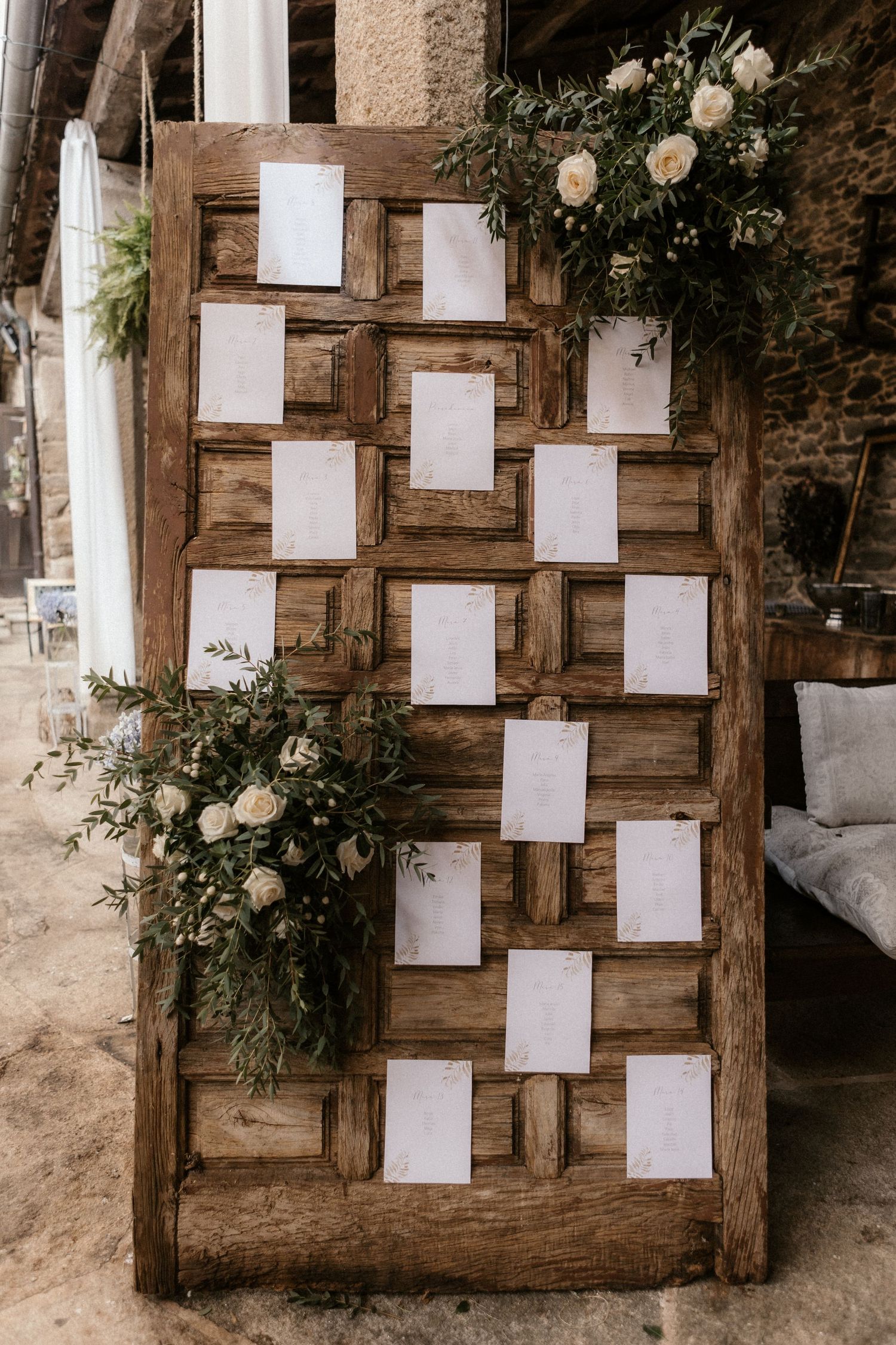 A rustic wooden seating chart display with blank white cards arranged on weathered wood panels.