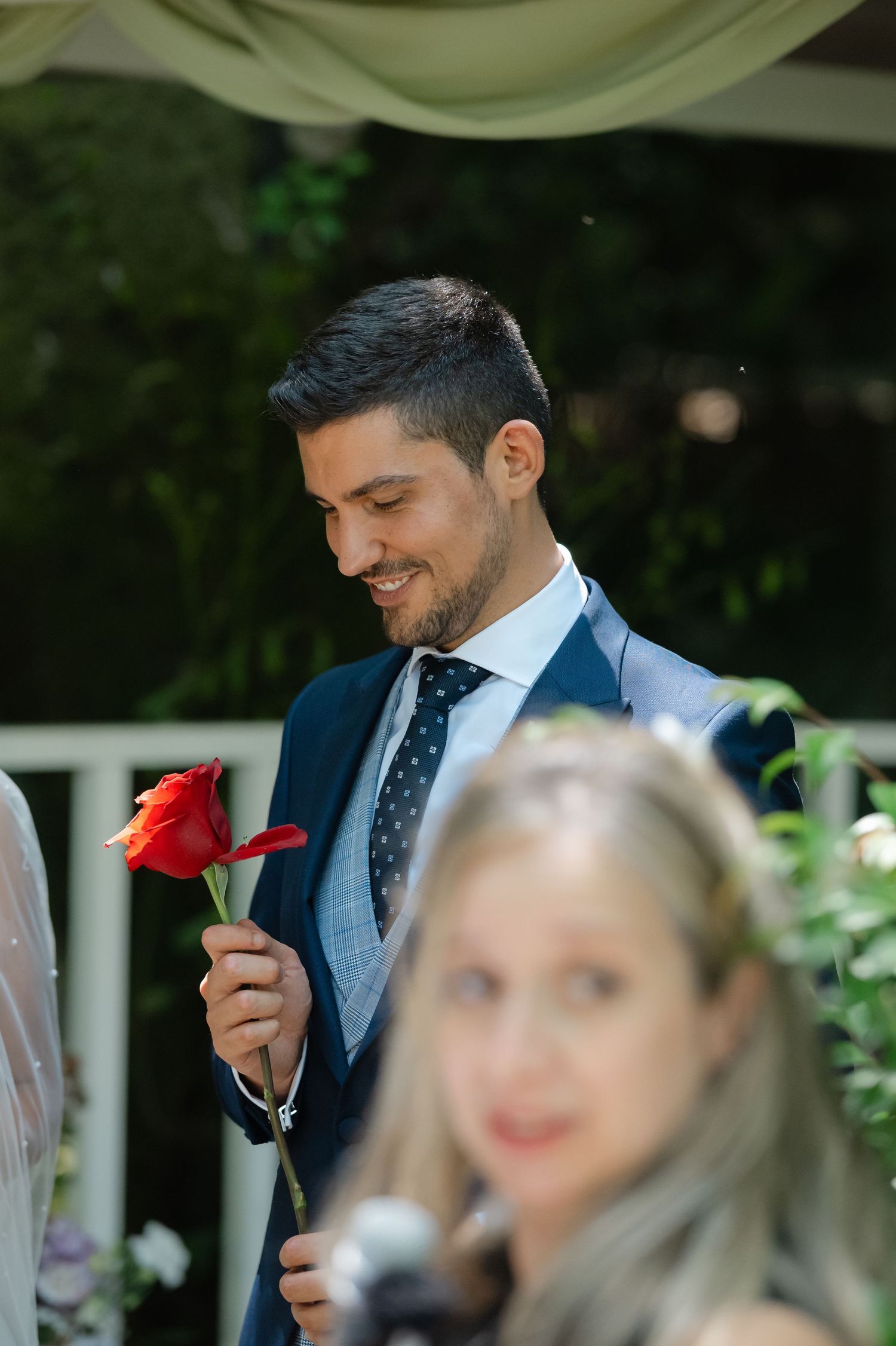 Wedding ceremony outdoors with couple and guests gathered under natural lighting.