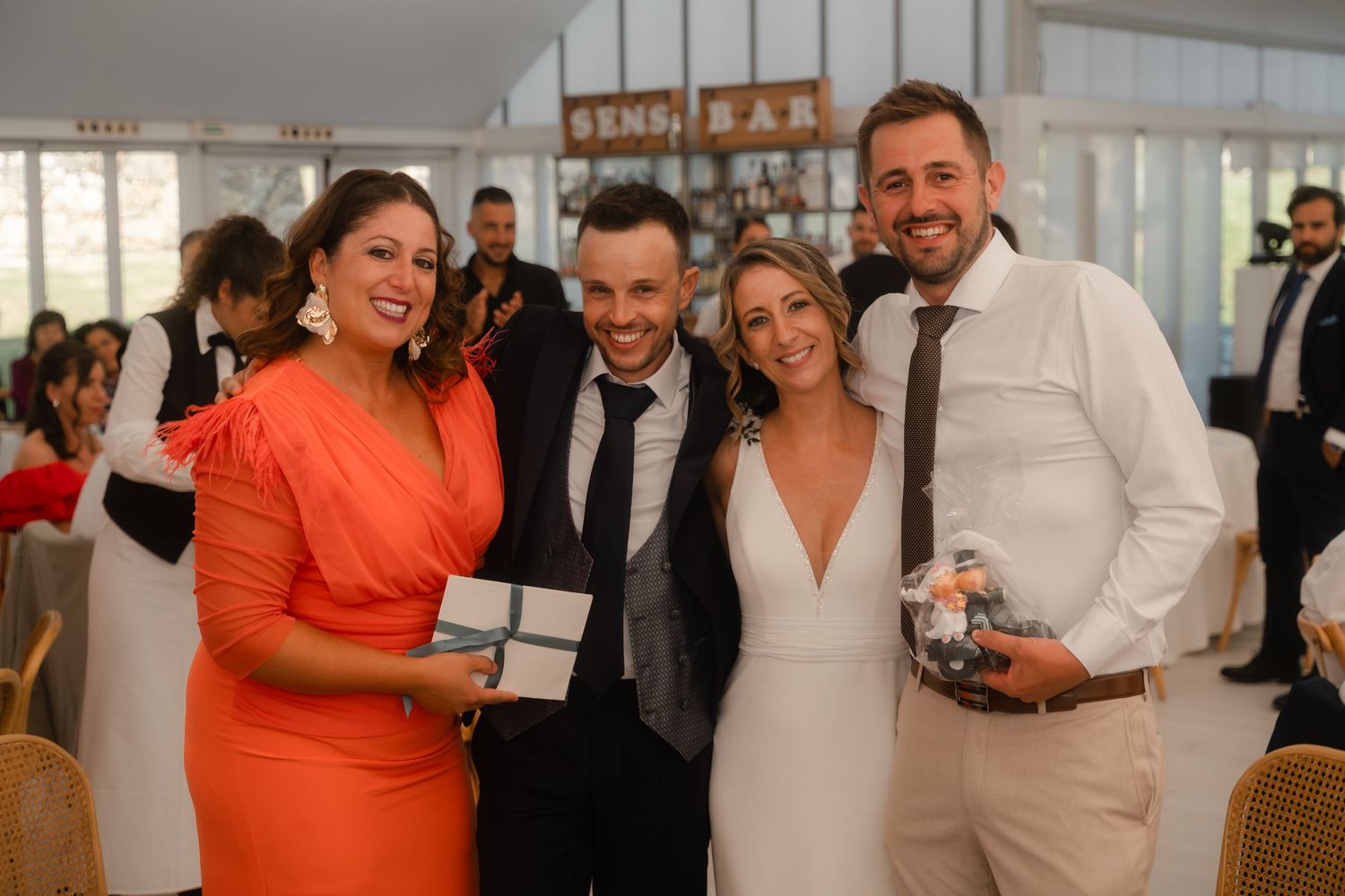 Wedding guests share joyful moments and laughter during a celebration at an elegant indoor venue.