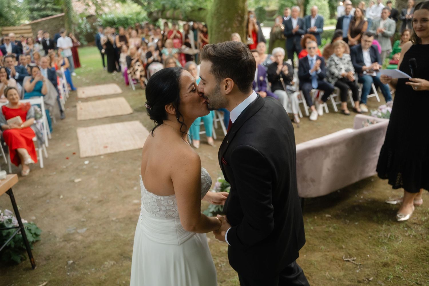 Large group of wedding guests gather outdoors for a celebratory moment.