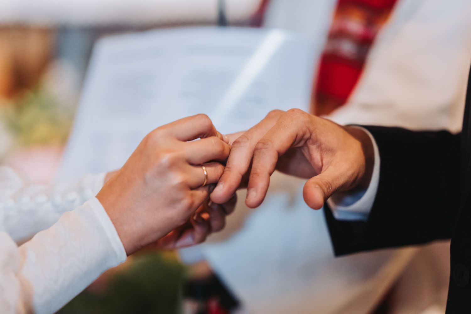 Close-up view of hands exchanging rings during a wedding ceremony.