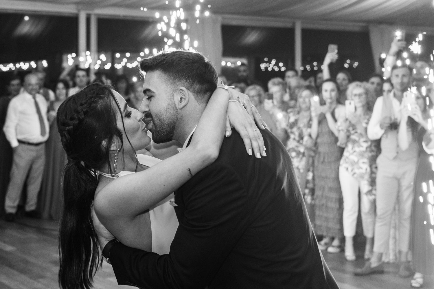 A romantic black and white photo of a couple sharing their first dance at their wedding reception.