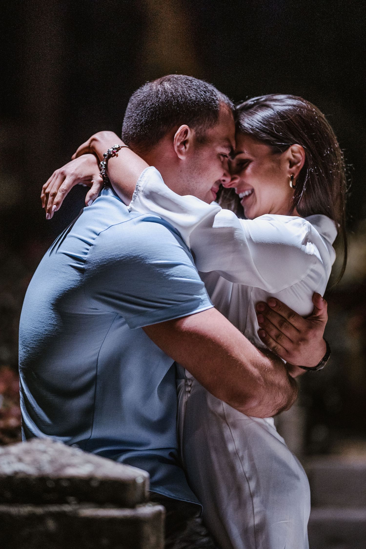 Two people sharing an intimate embrace in a romantic outdoor setting.