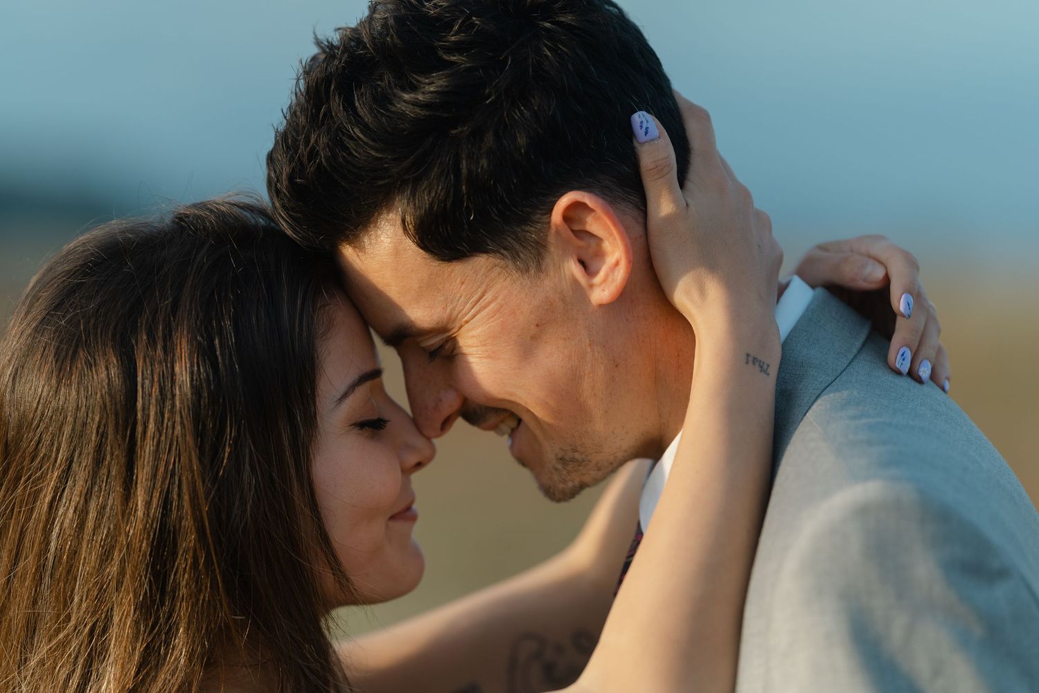 A loving couple share an intimate forehead-to-forehead moment outdoors in soft natural light.