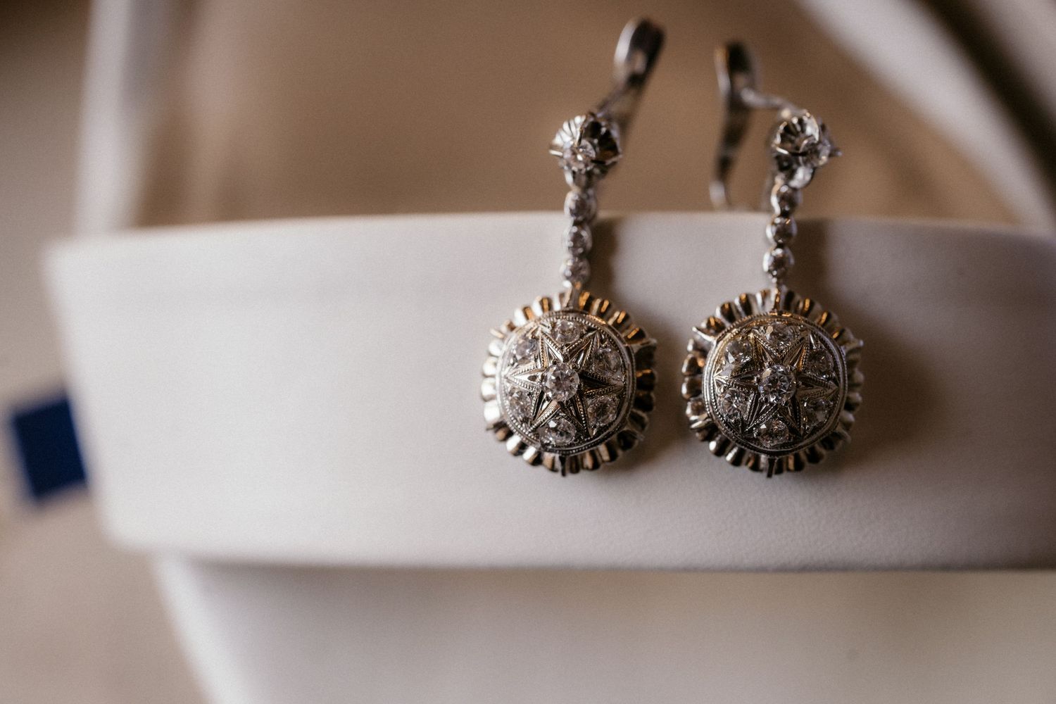 Elegant silver and crystal bridal earrings with intricate floral design displayed on white surface.