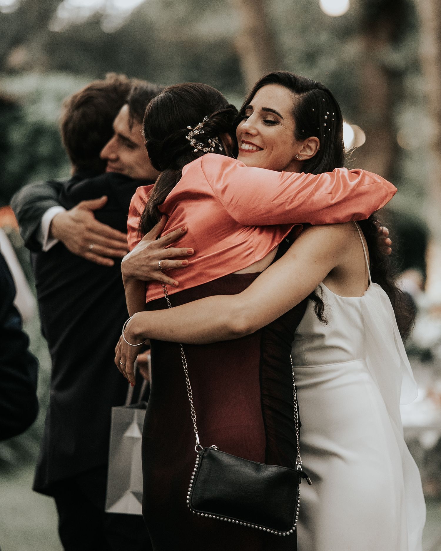 Wedding guests share warm embraces and hugs during an outdoor celebration.