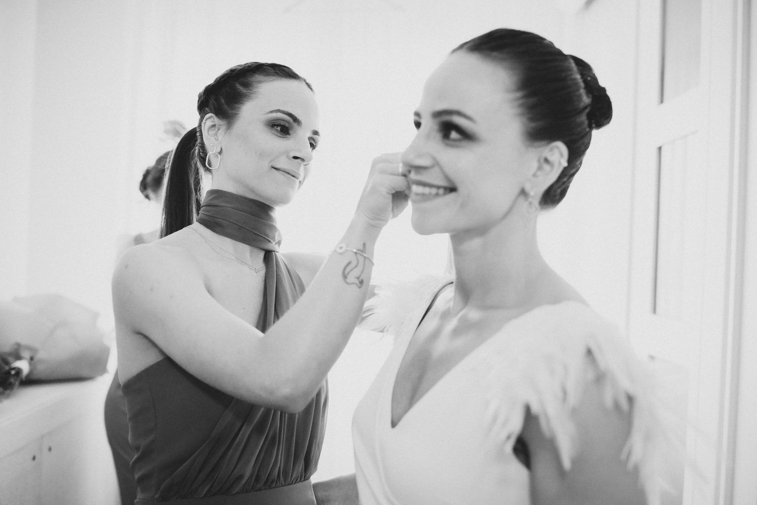 Wedding preparations scene showing makeup application and styling in a bright white interior setting.