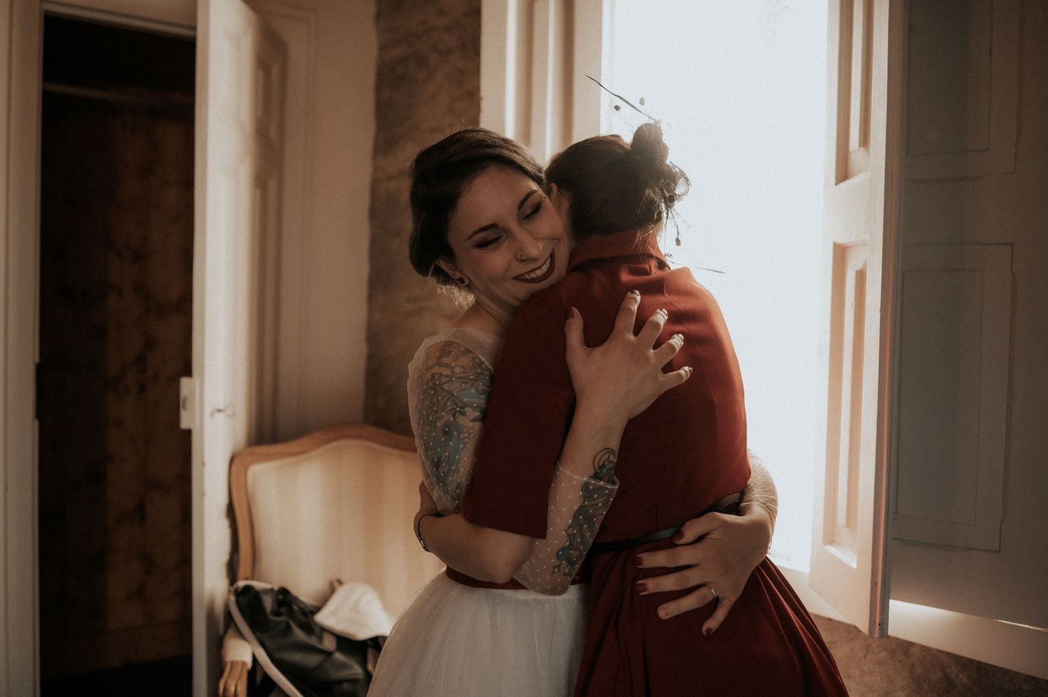 A couple embraces intimately in warm lighting near a window during a romantic moment.