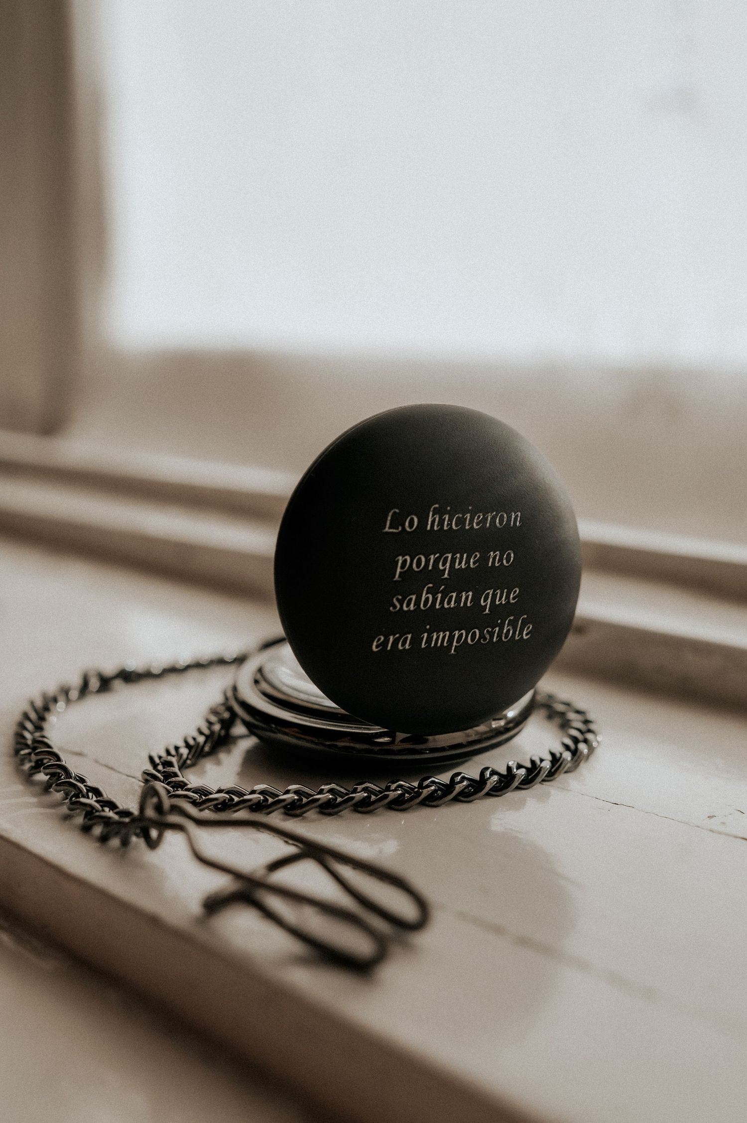 A vintage pocket watch with chain lies on a surface in sepia tones, shown from four different artistic angles.