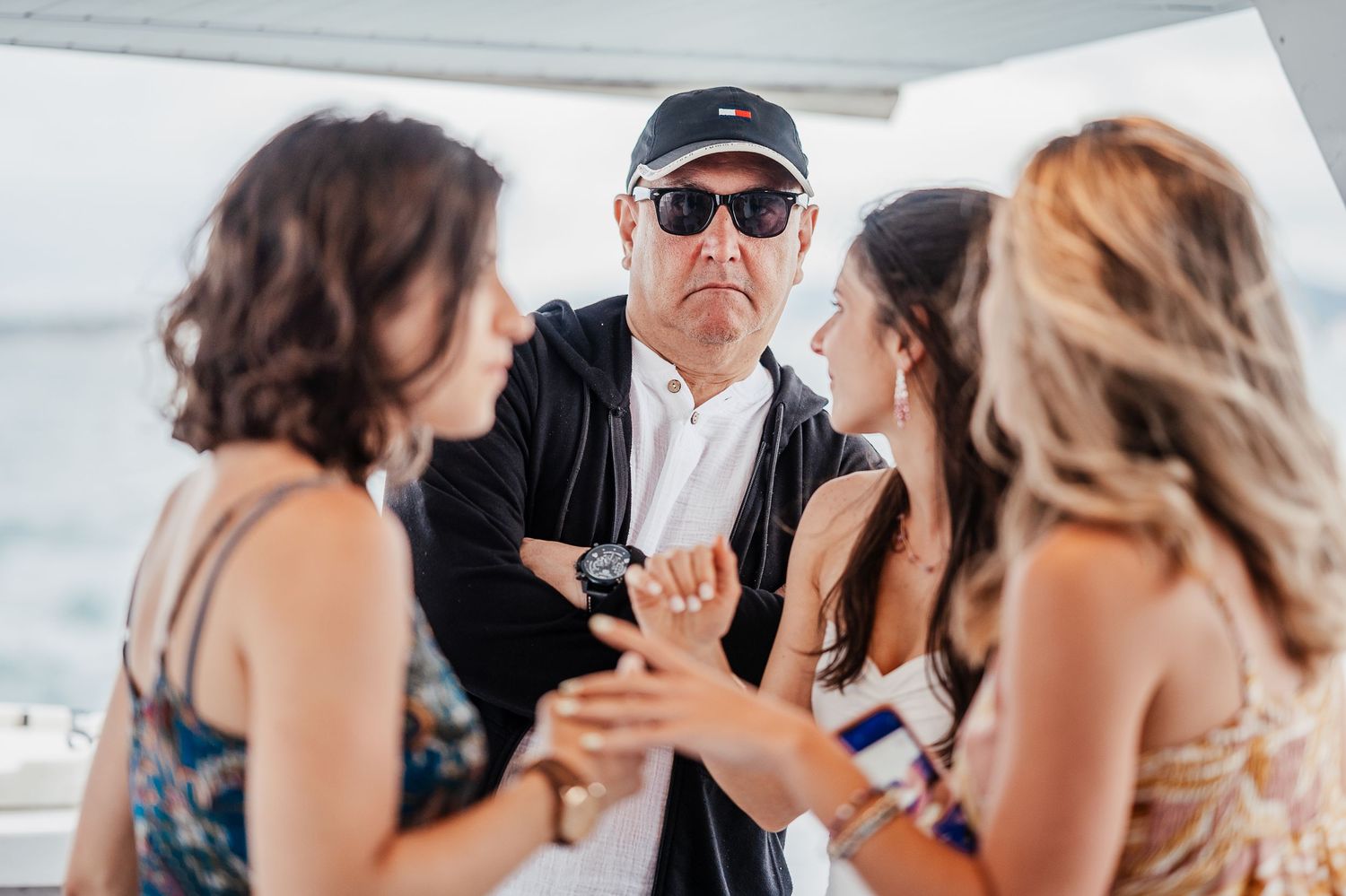 Group enjoying a festive celebration on a boat deck with sunglasses and summer attire.