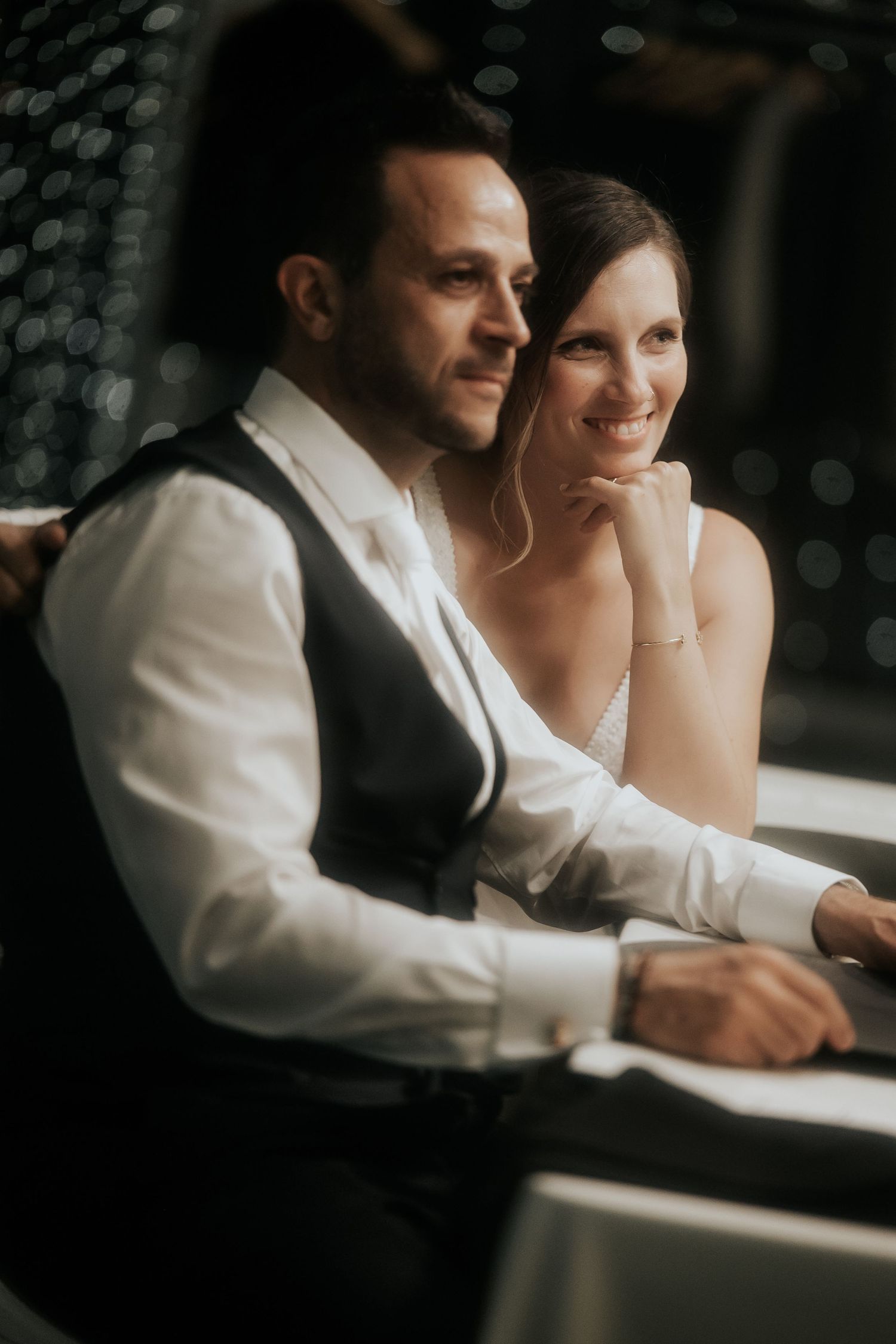 A couple signs documents together at a table in formal attire.