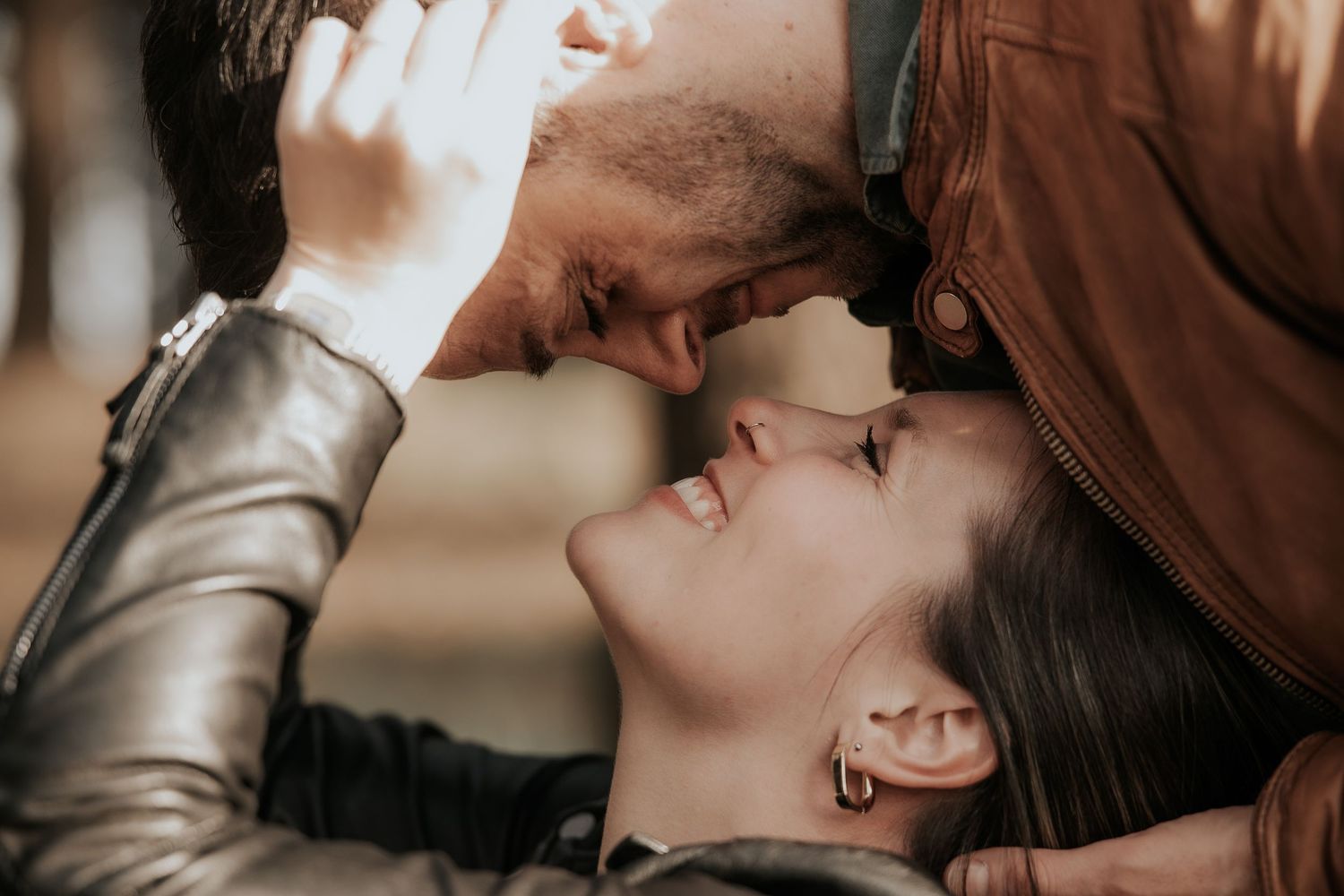 A romantic couple shares an intimate kiss in a warm, sepia-toned setting.