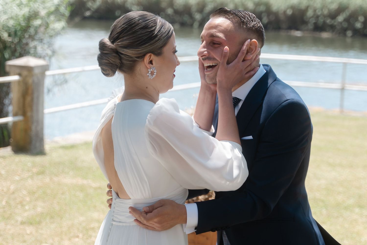 A tender moment between a couple during their outdoor wedding celebration by the water.