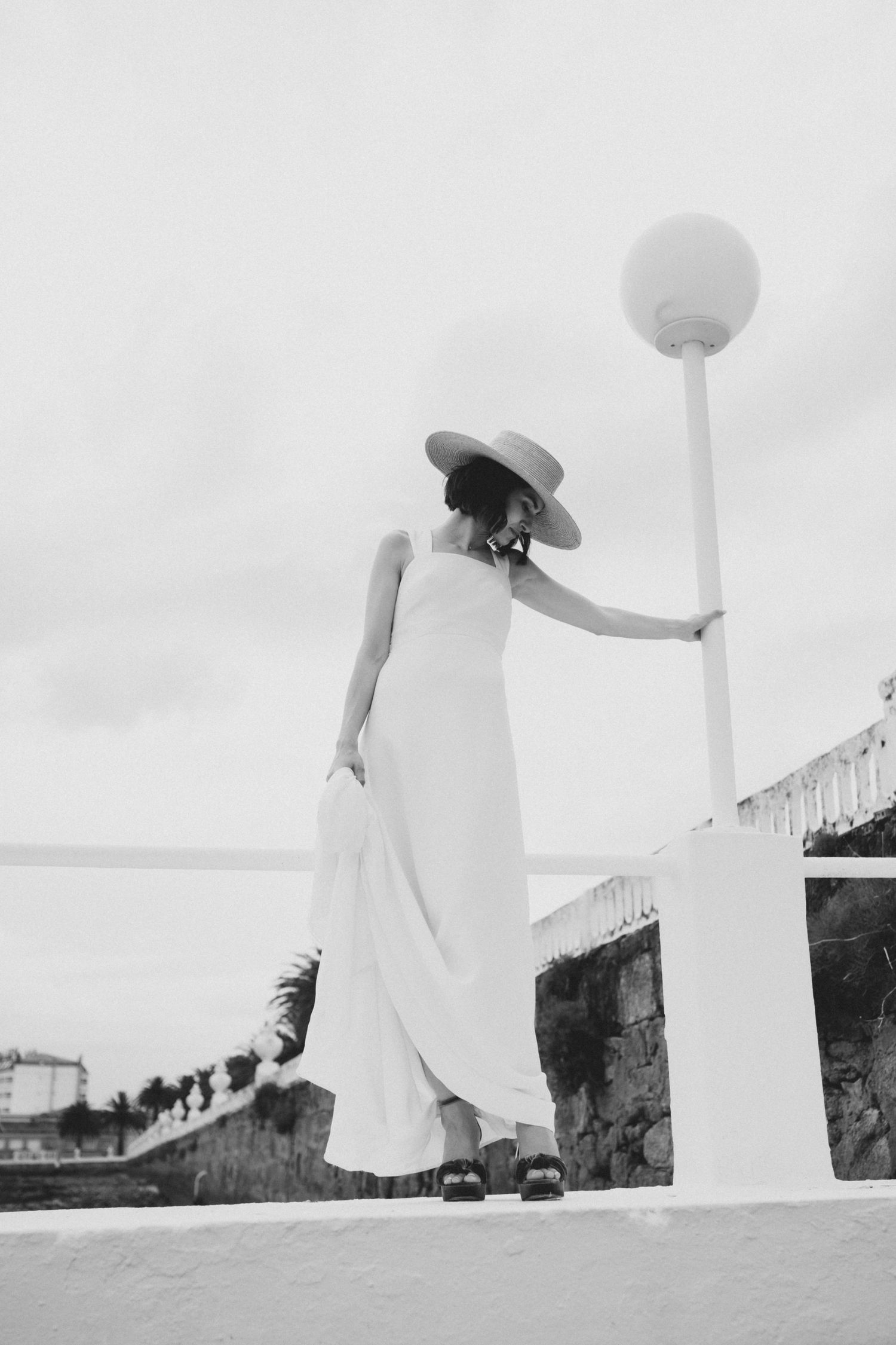 A series of four black and white photographs showing ethereal white-clad figures against a stark landscape background.