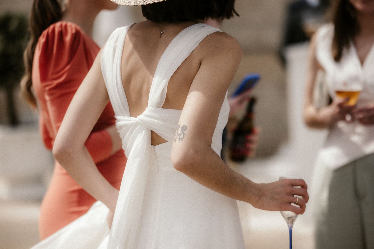 Candid moments captured at an outdoor wedding with guests in coral and white attire.