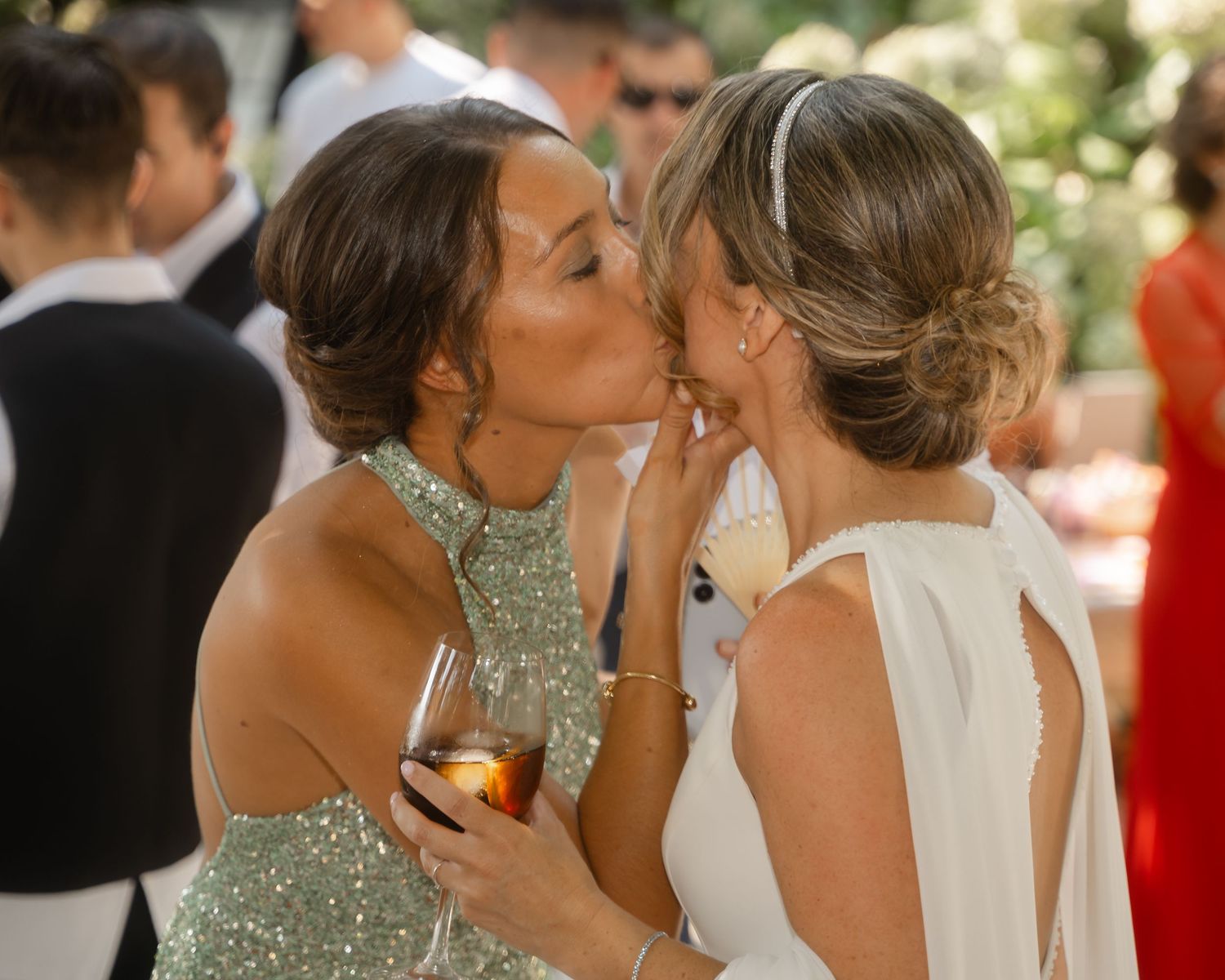 Wedding party members share emotional embraces during outdoor celebration.