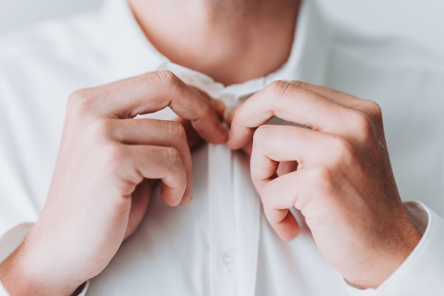 Close-up sequence of hands opening a small white pill bottle with safety cap against light background.