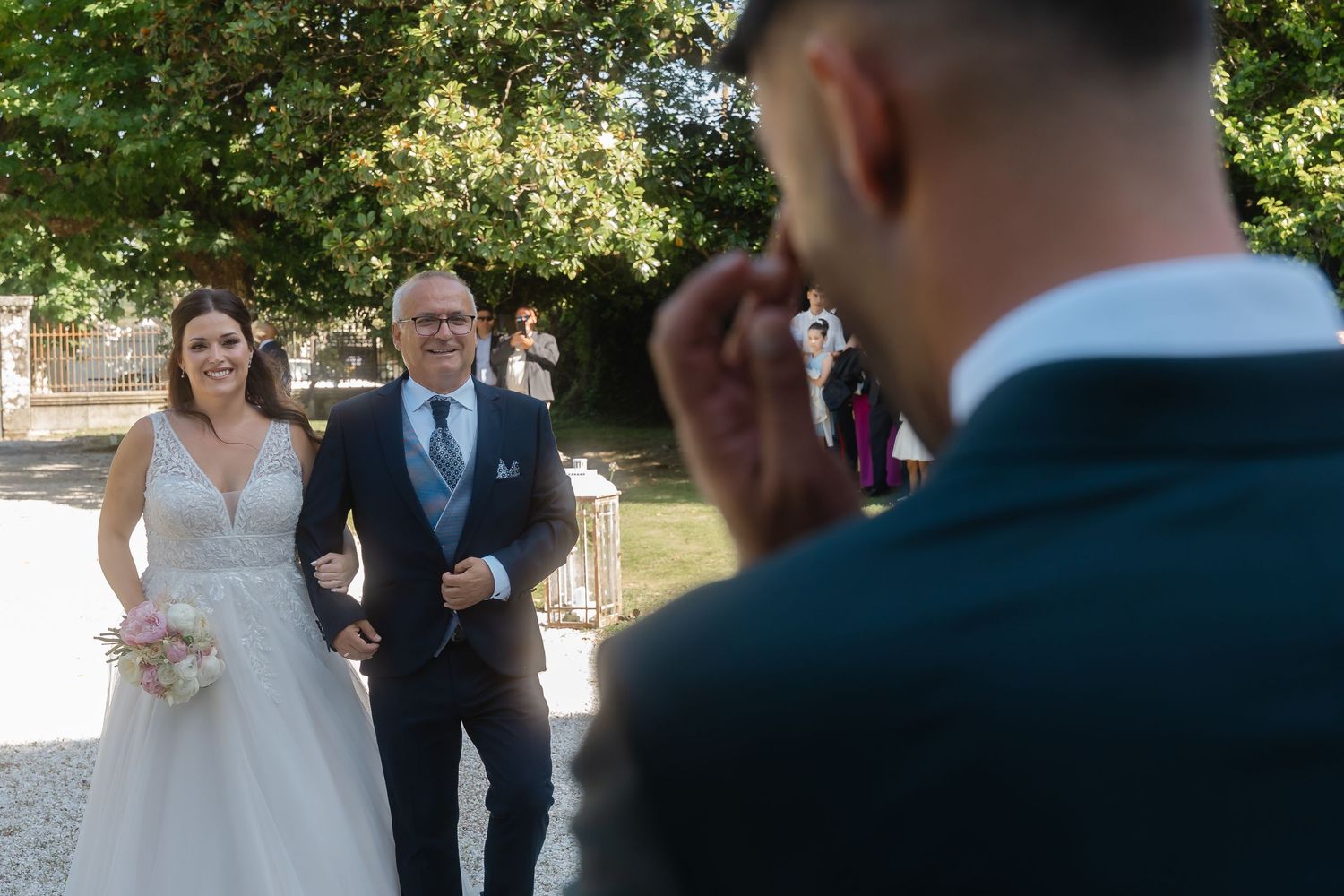 Wedding ceremony processional on a sunny outdoor lawn with white chairs.