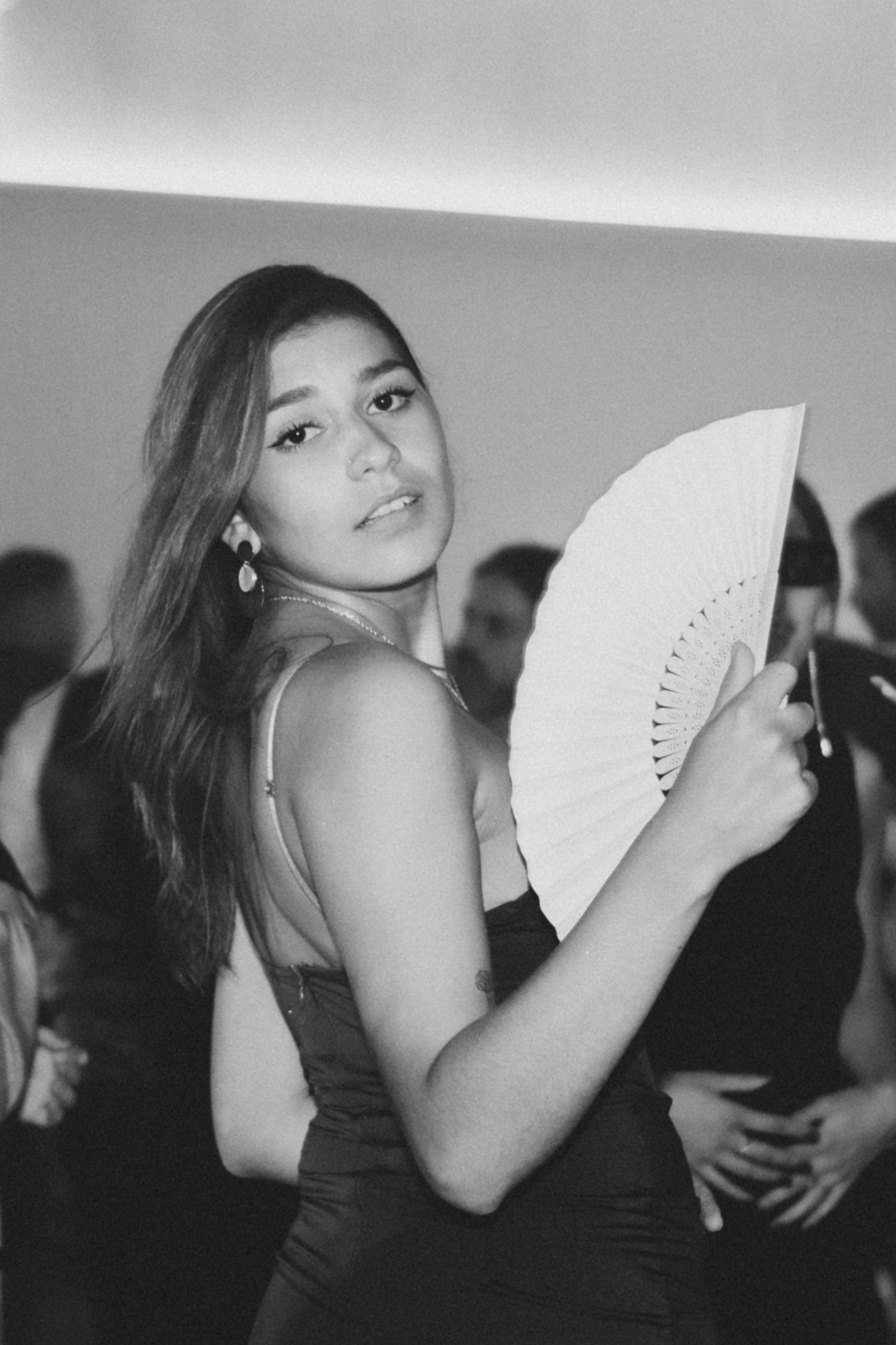 A series of black and white photos showing someone posing gracefully with a decorative folding fan.