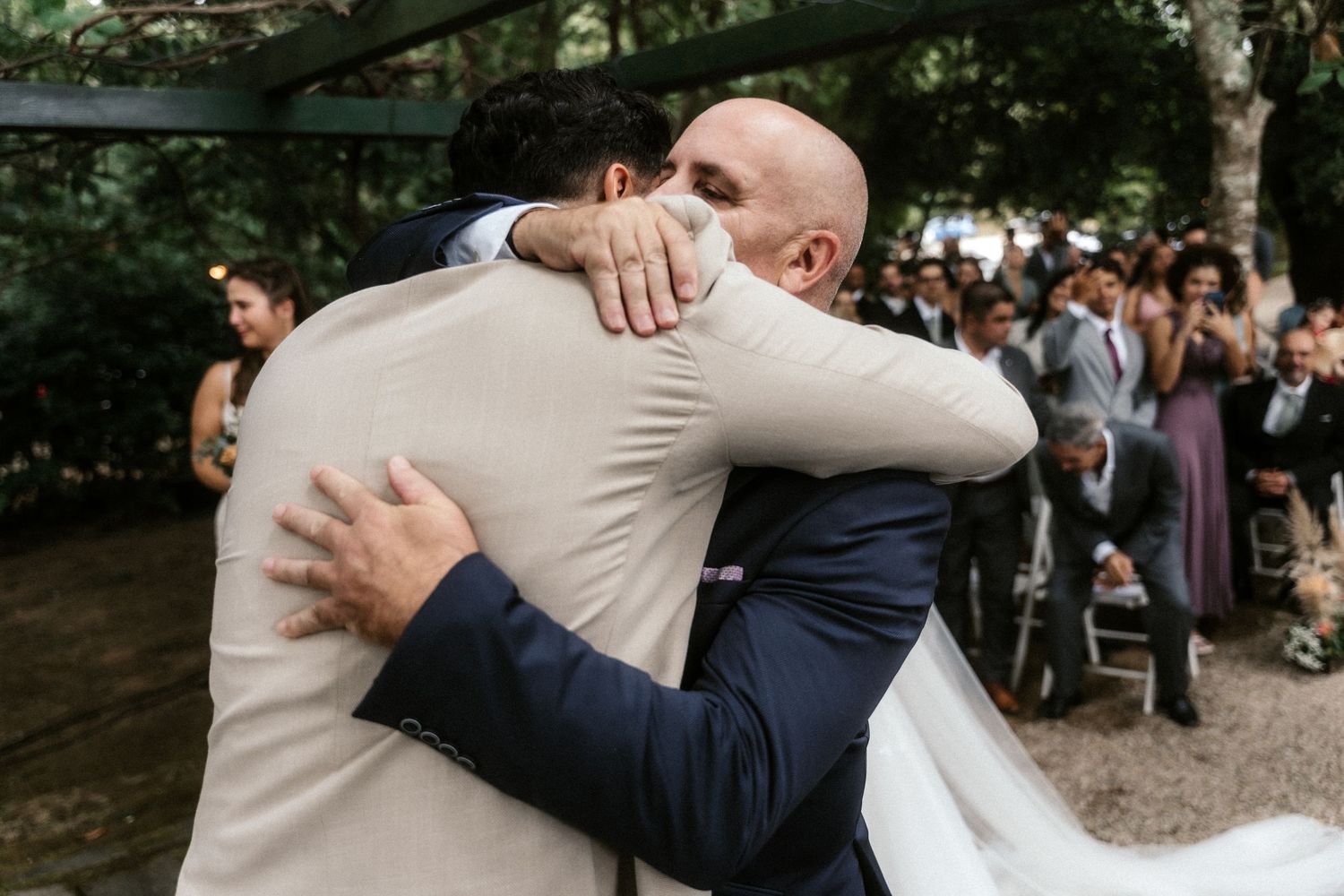 Emotional wedding ceremony moment in a wooded outdoor setting with guests looking on.