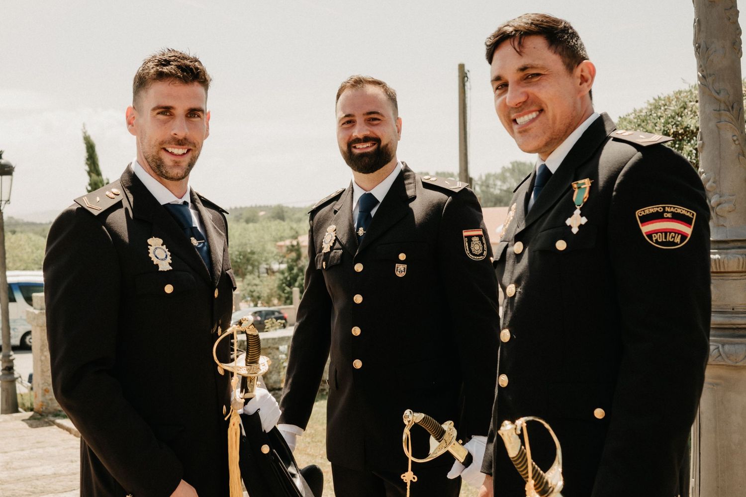 Military service members in dress uniforms smile and celebrate at an outdoor wedding ceremony.