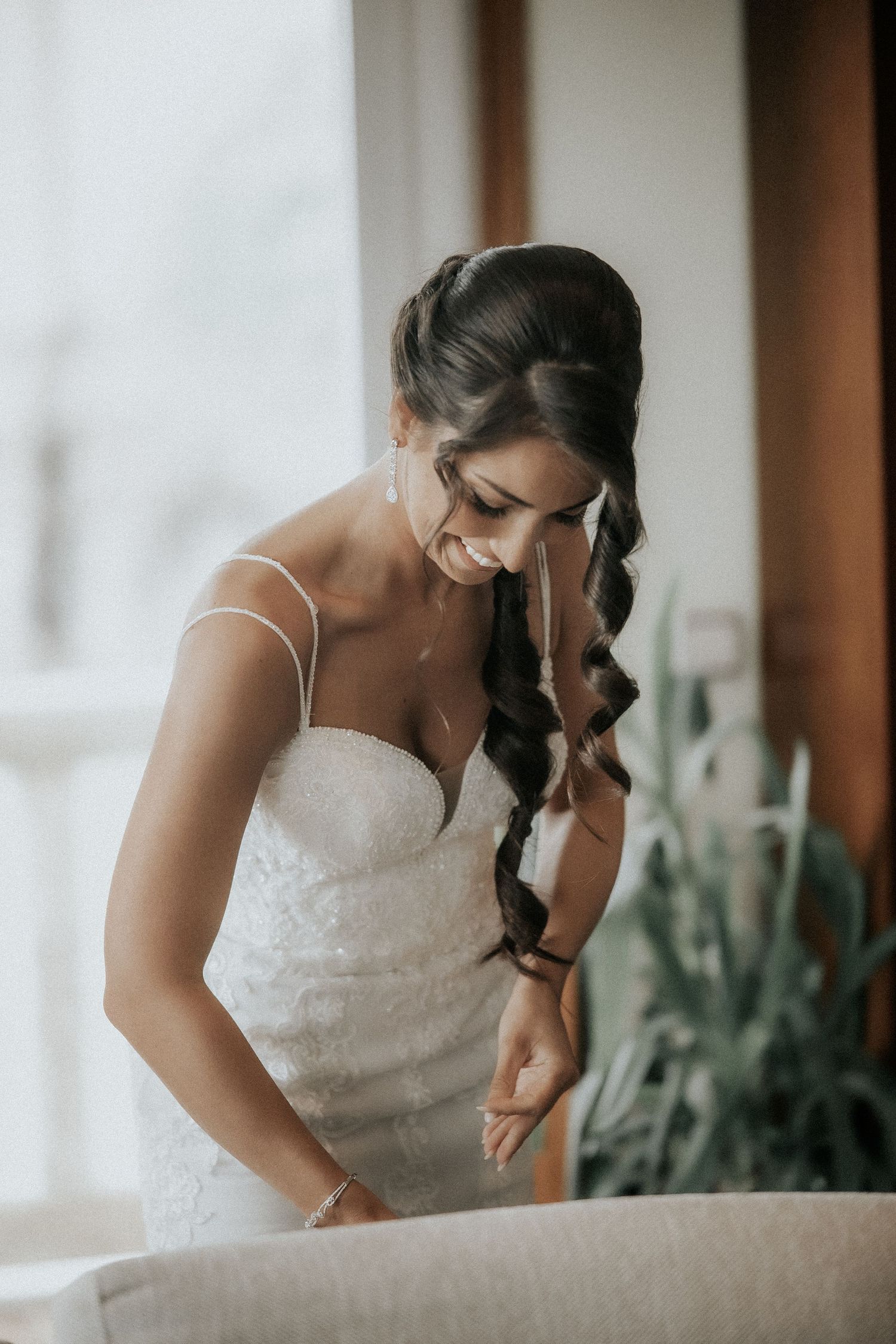 A white lace wedding dress being worn while sitting in an elegant indoor setting.