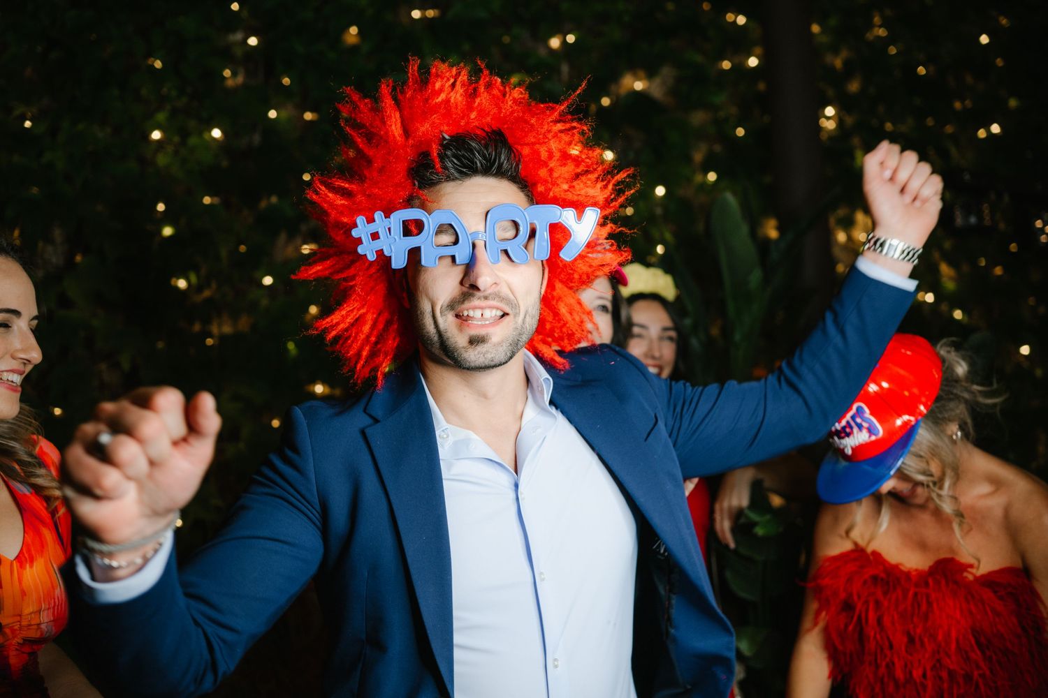 People dancing and celebrating at a party with festive red decorations and lighting.