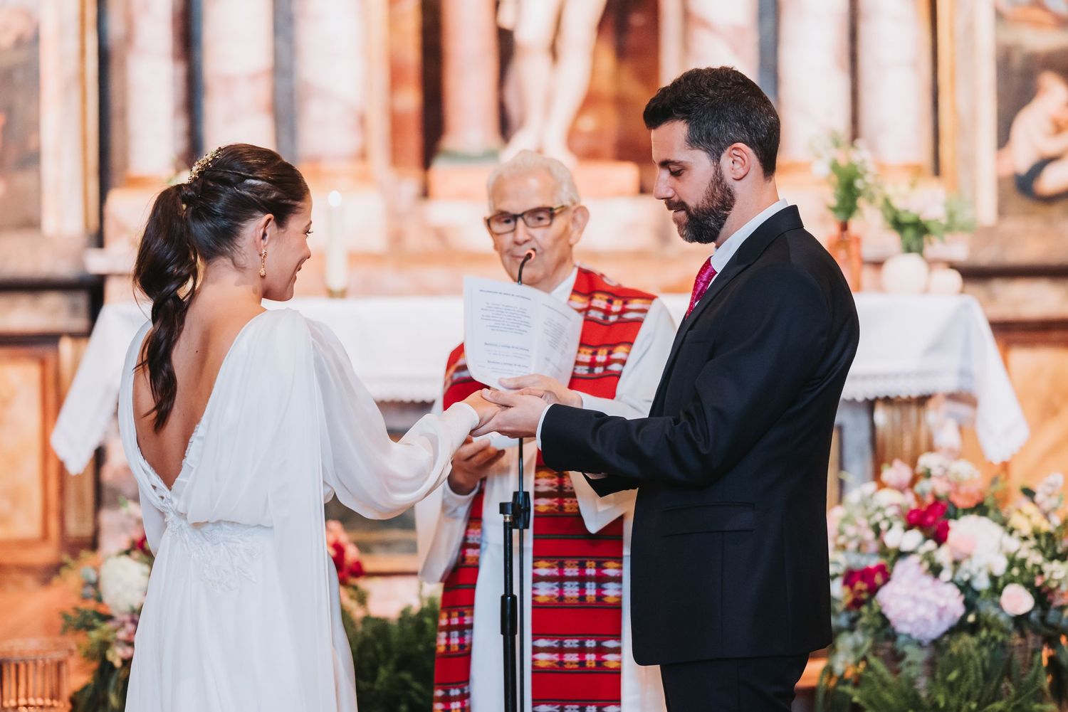 Wedding guests mingling and celebrating in front of ornate pink church entrance.