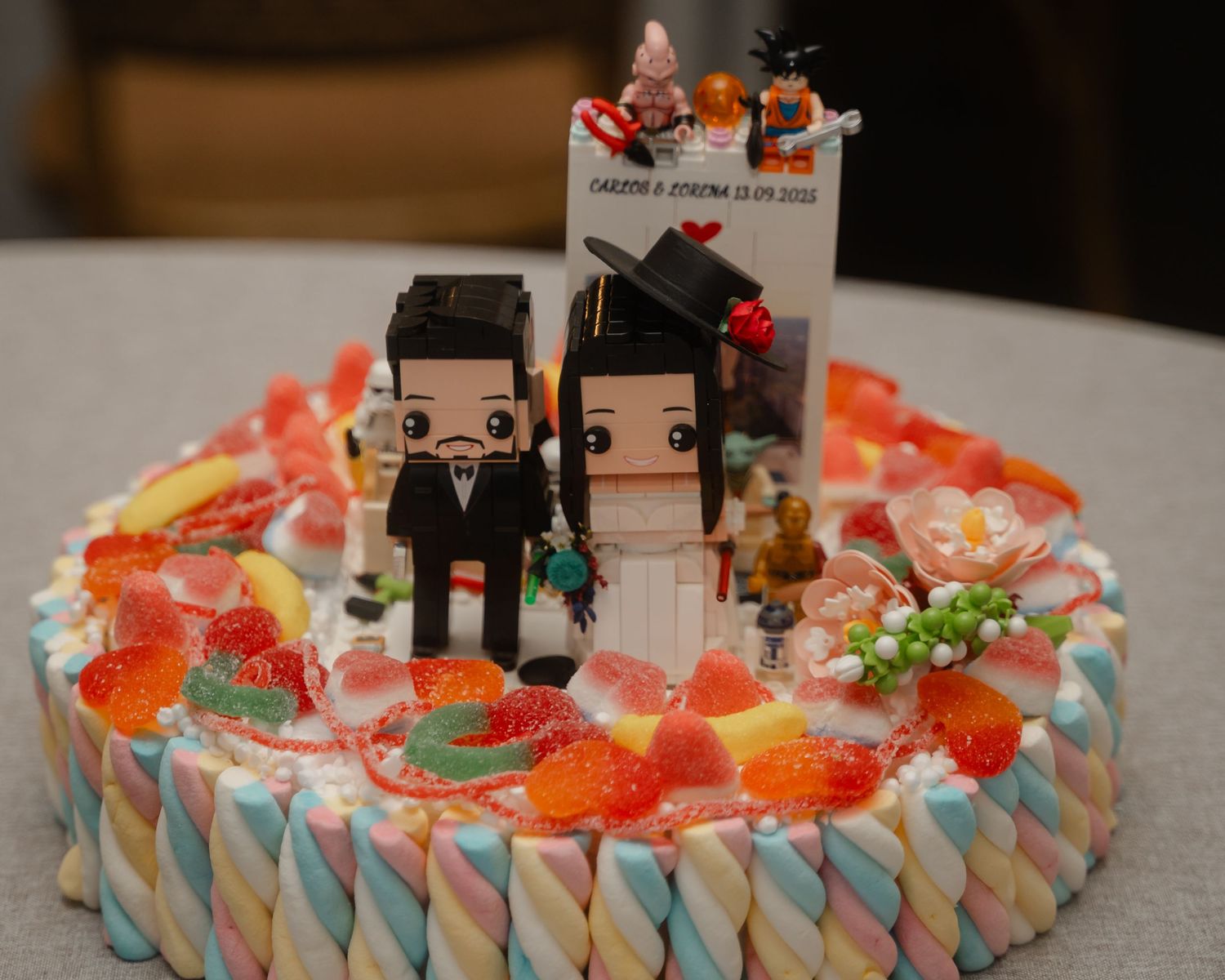 Colorful candy and marshmallow decorated cake displayed at a wedding reception.