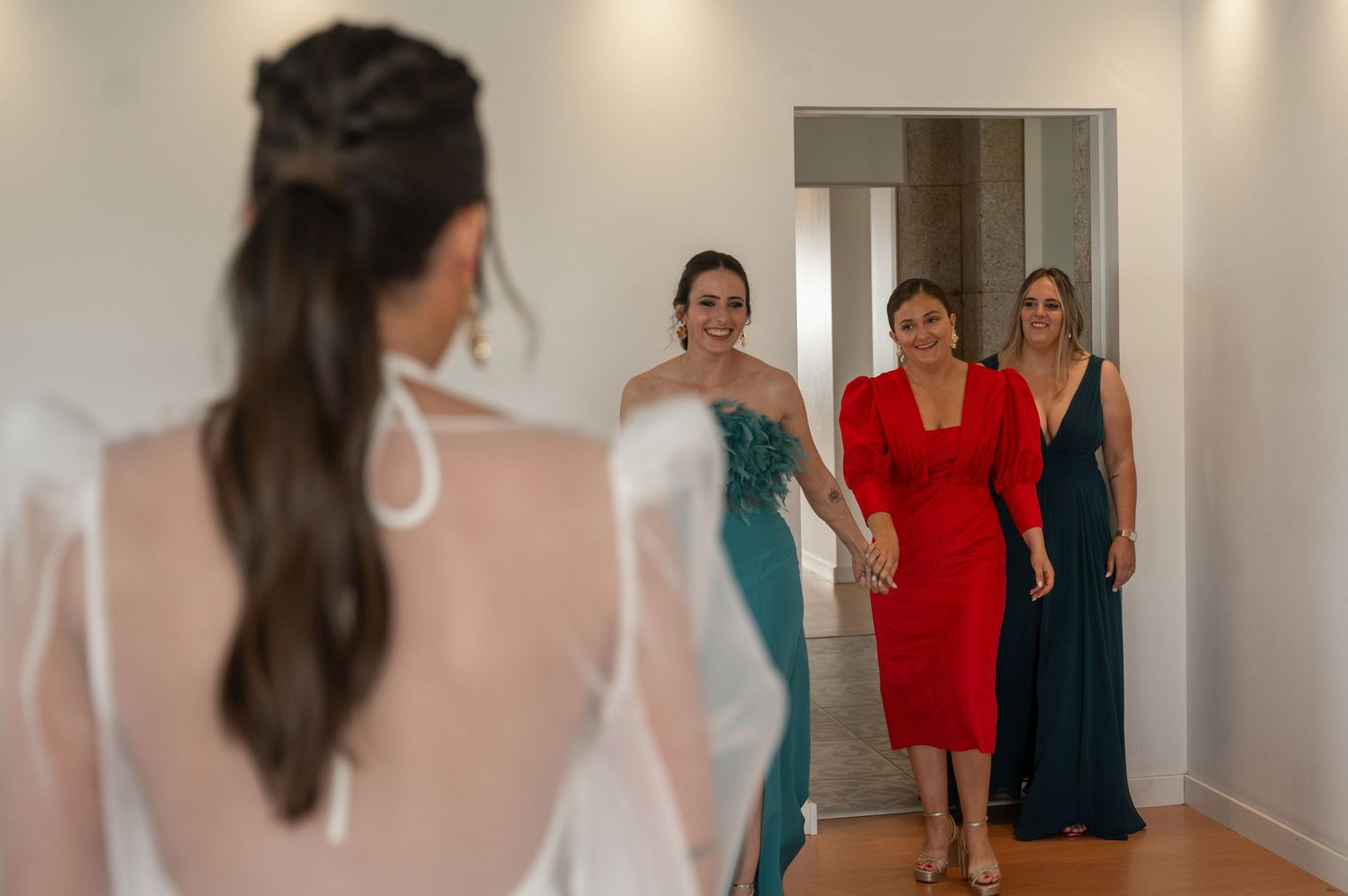 A group of women in colorful dresses walk down a hallway in a series of connected photos.