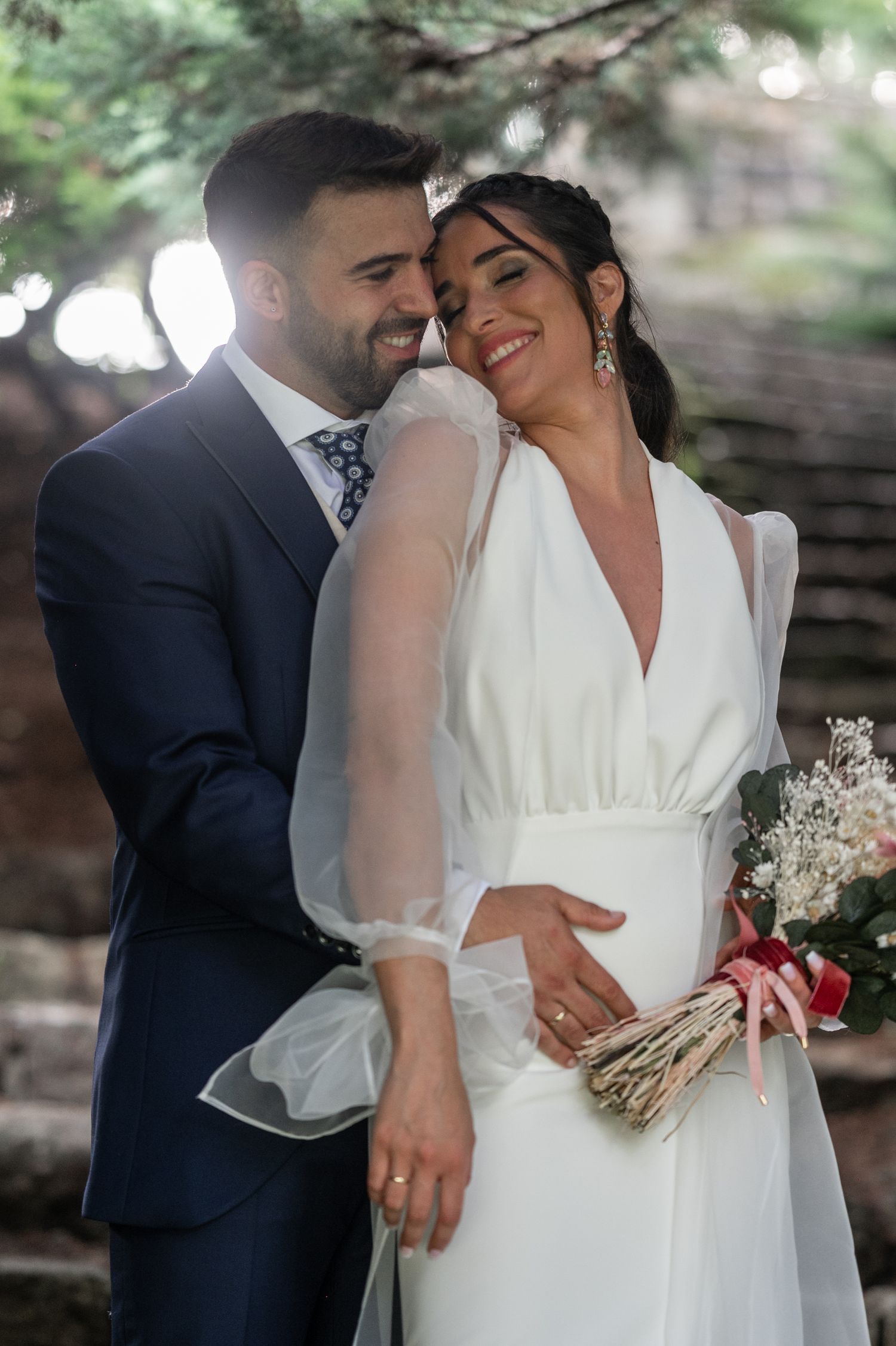A romantic wedding couple shares intimate moments in a natural outdoor setting with soft lighting and greenery.