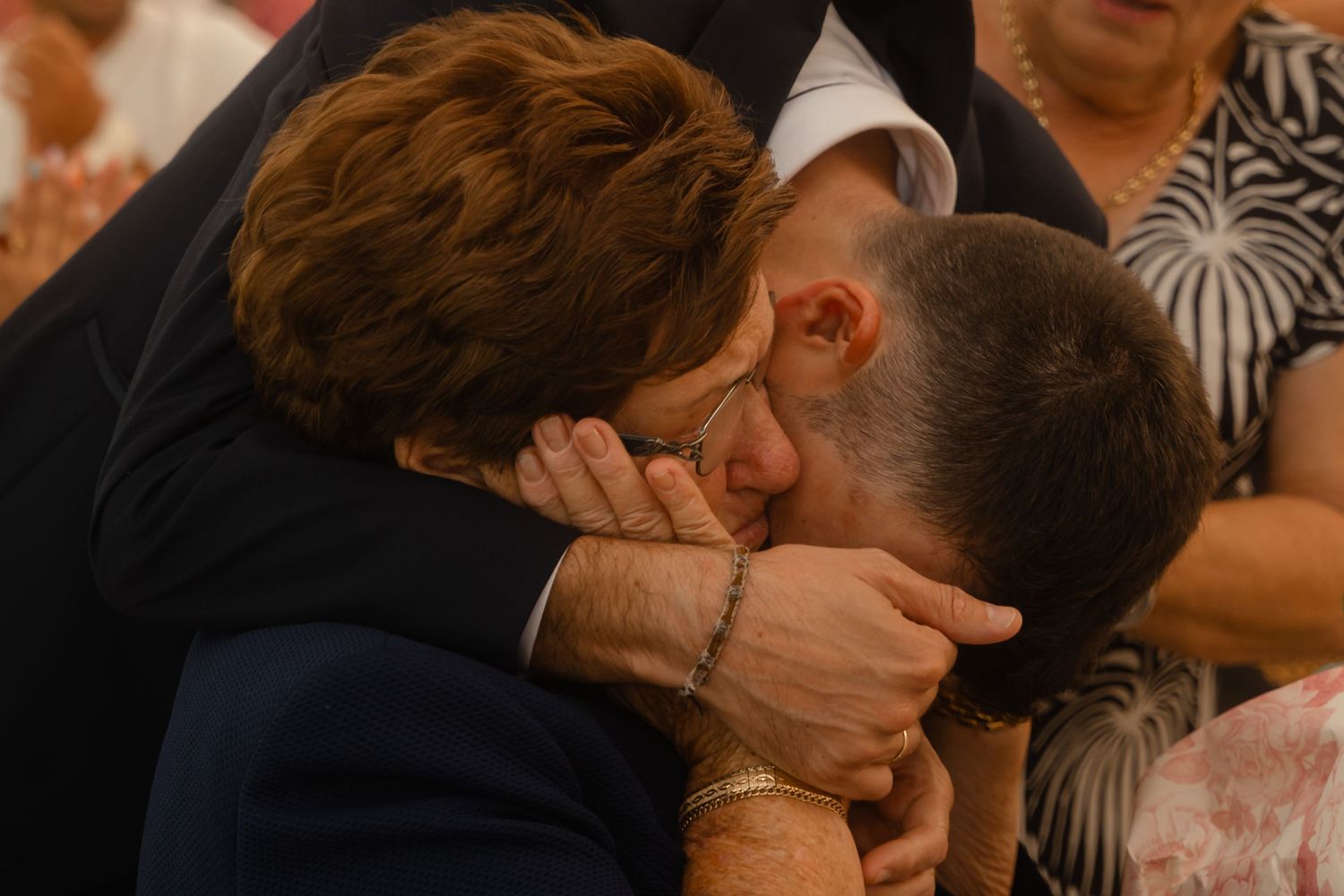 Wedding guests embrace emotionally during a heartfelt reception moment.
