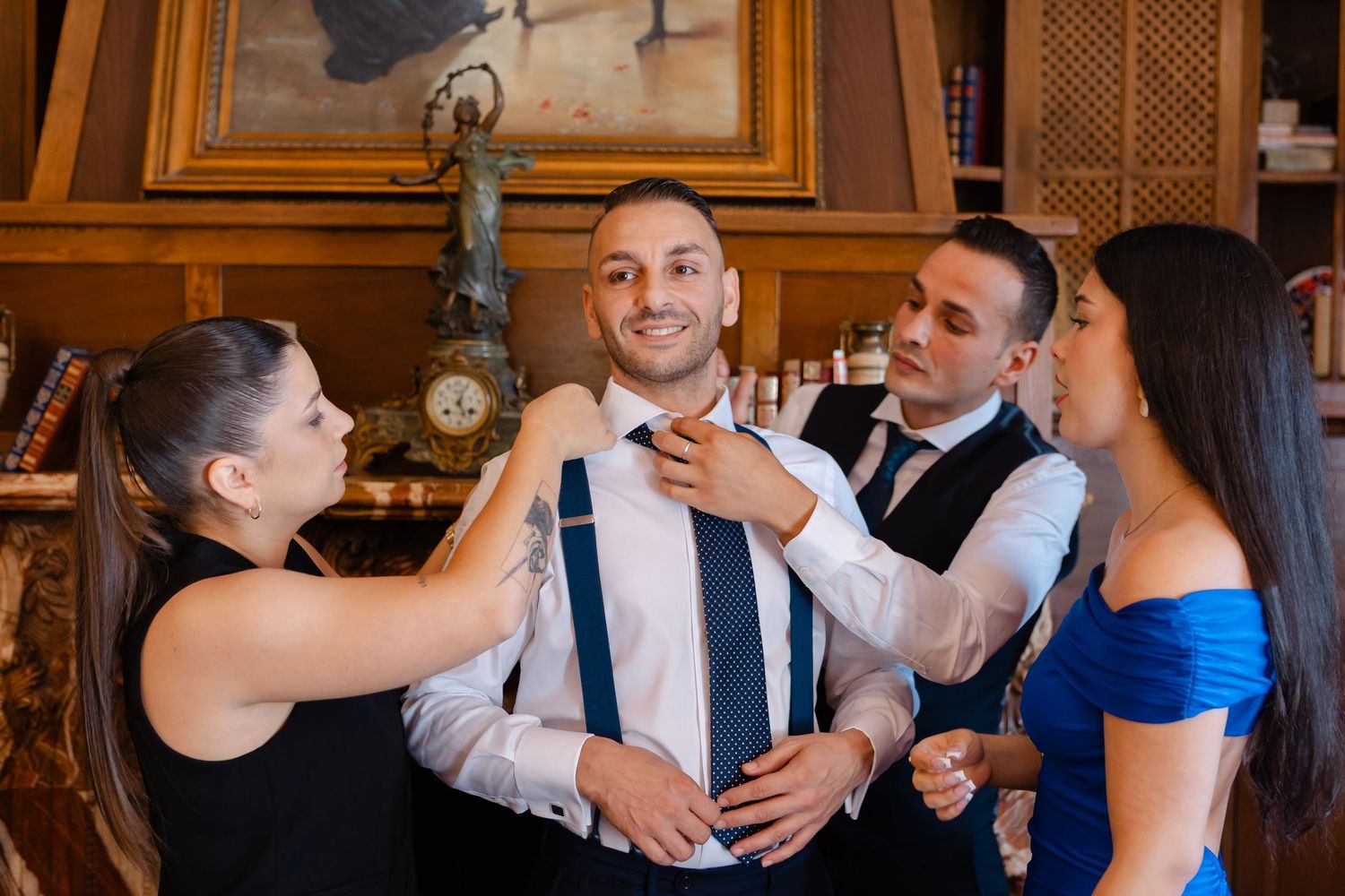 Wedding party members share a joyful group hug during celebration at an elegant indoor venue.