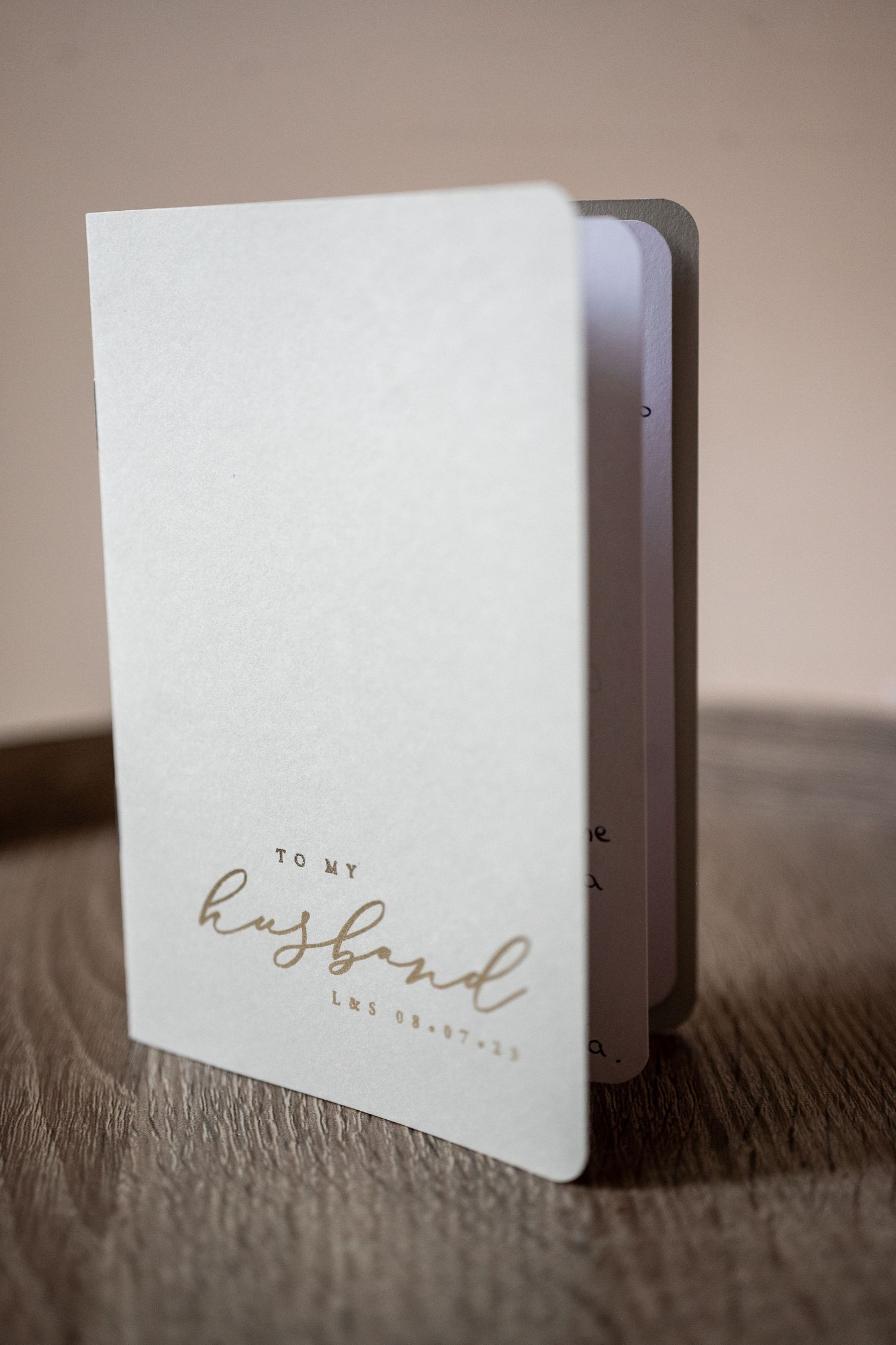Minimalist white business cards with gold lettering displayed in a row on textured surface.