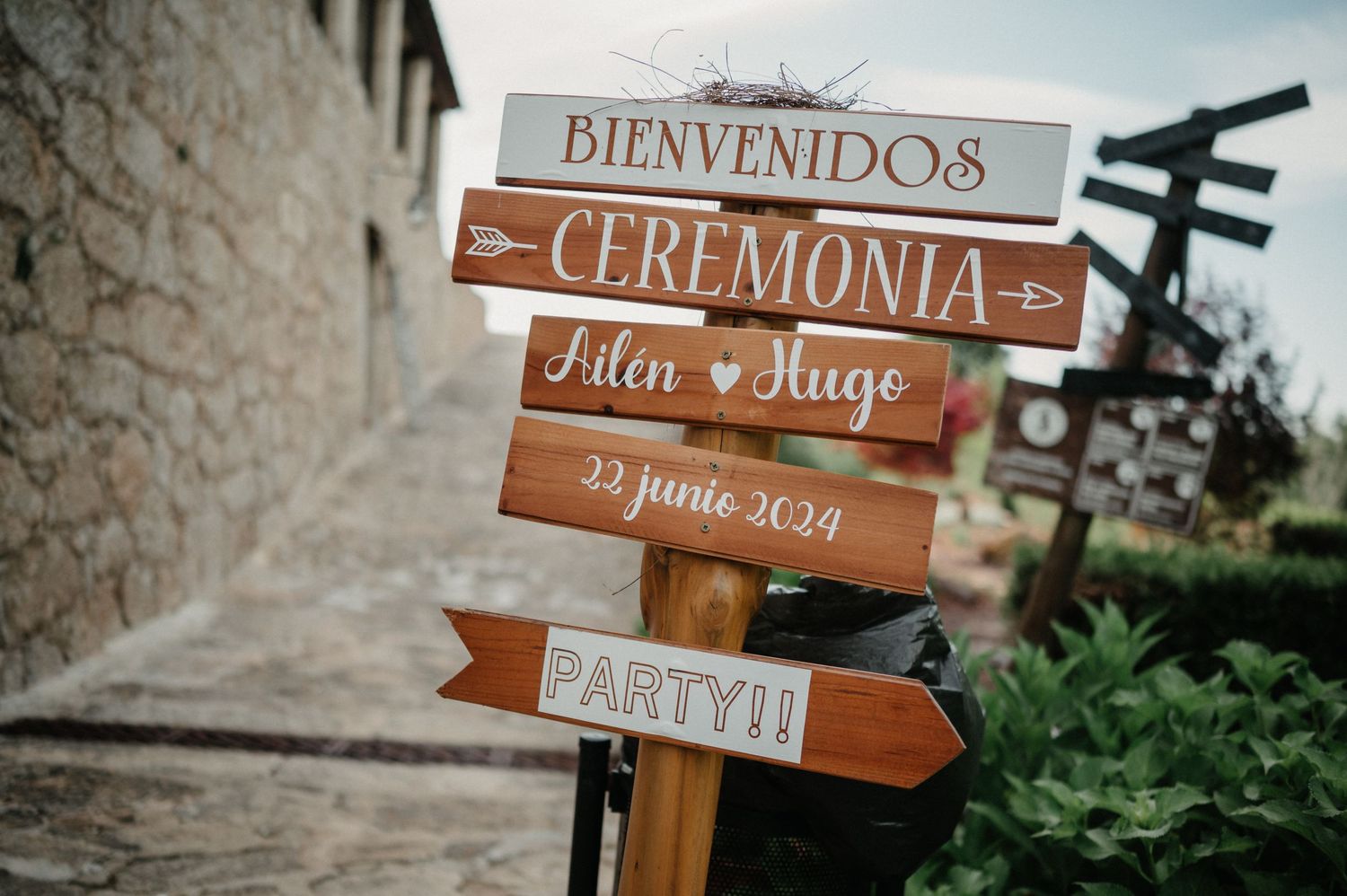 Rustic wooden directional signs with wedding-related text mounted on posts in an outdoor setting.