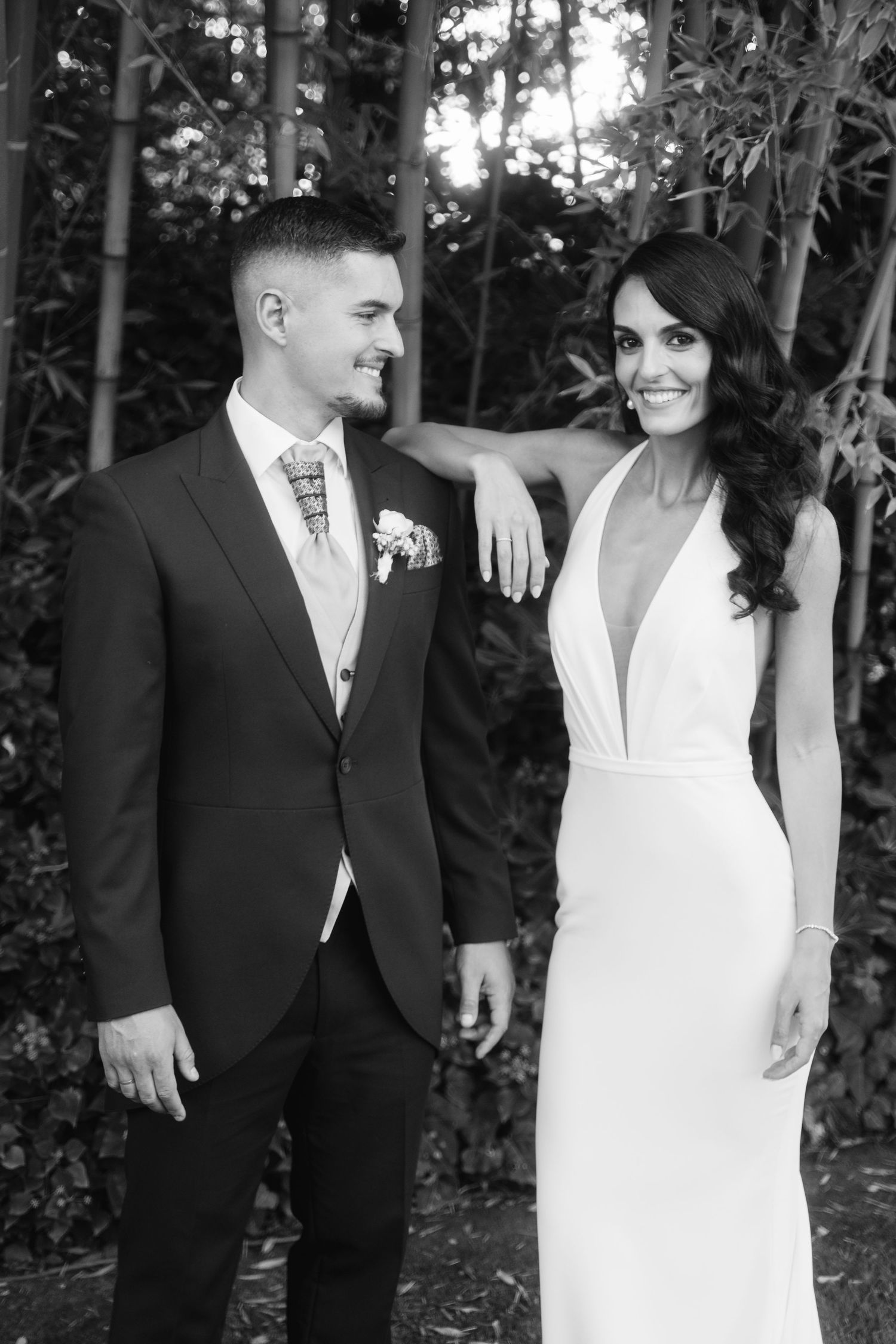 A happy couple shares a candid moment together outdoors in formal wedding attire.