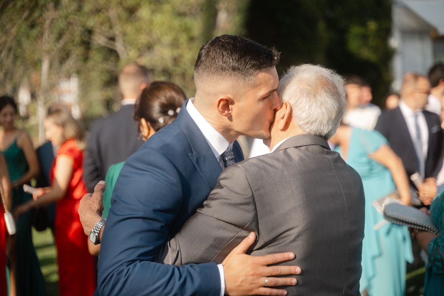 Wedding guests gather outdoors for a celebration with people mingling in formal attire.