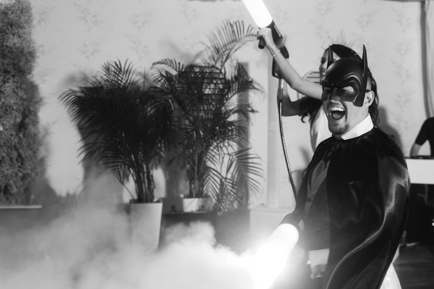 A performer in a Batman costume uses a fog machine during a dramatic black and white party moment.