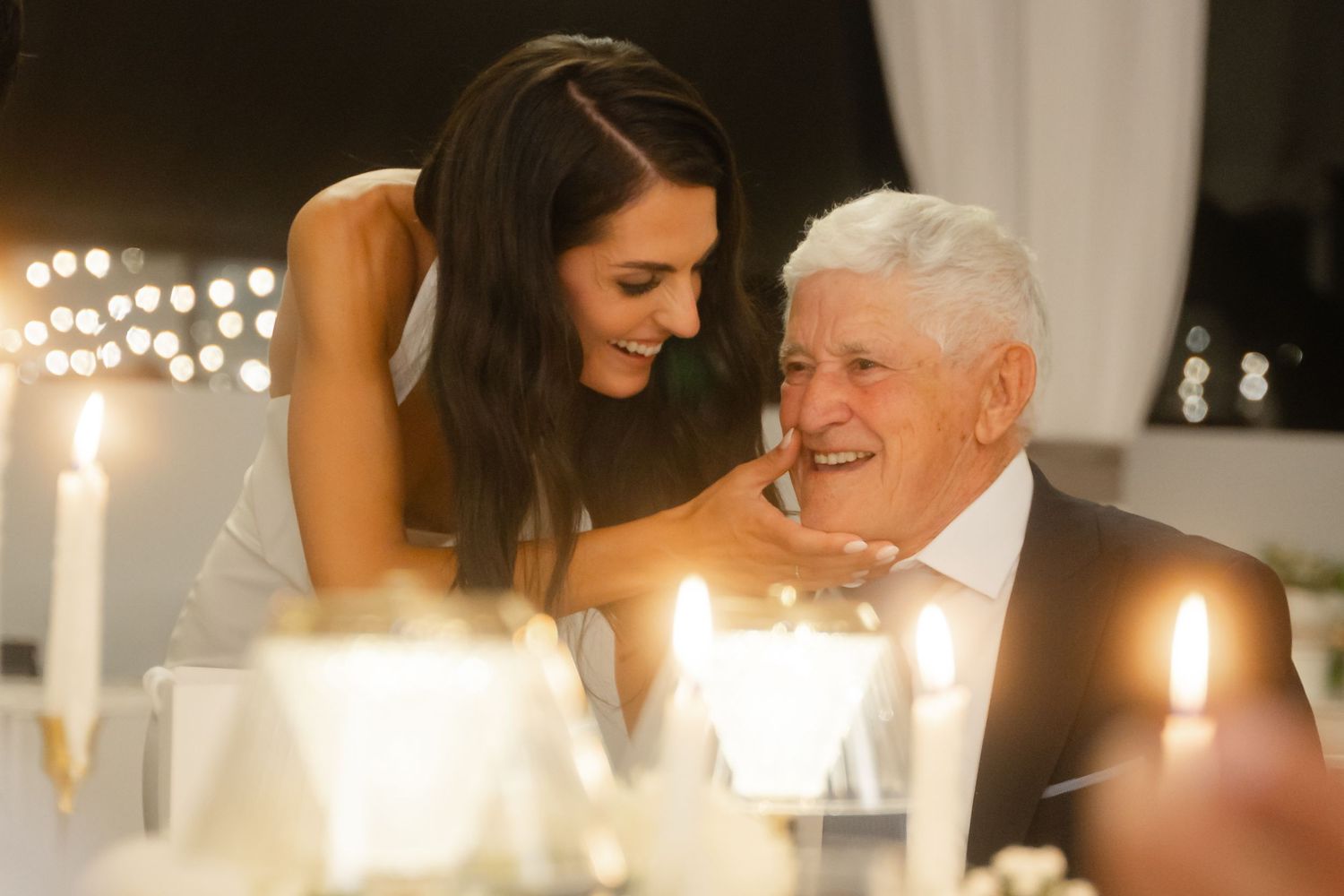 Candlelit wedding reception table with guests sharing joyful moments in an elegant indoor venue.