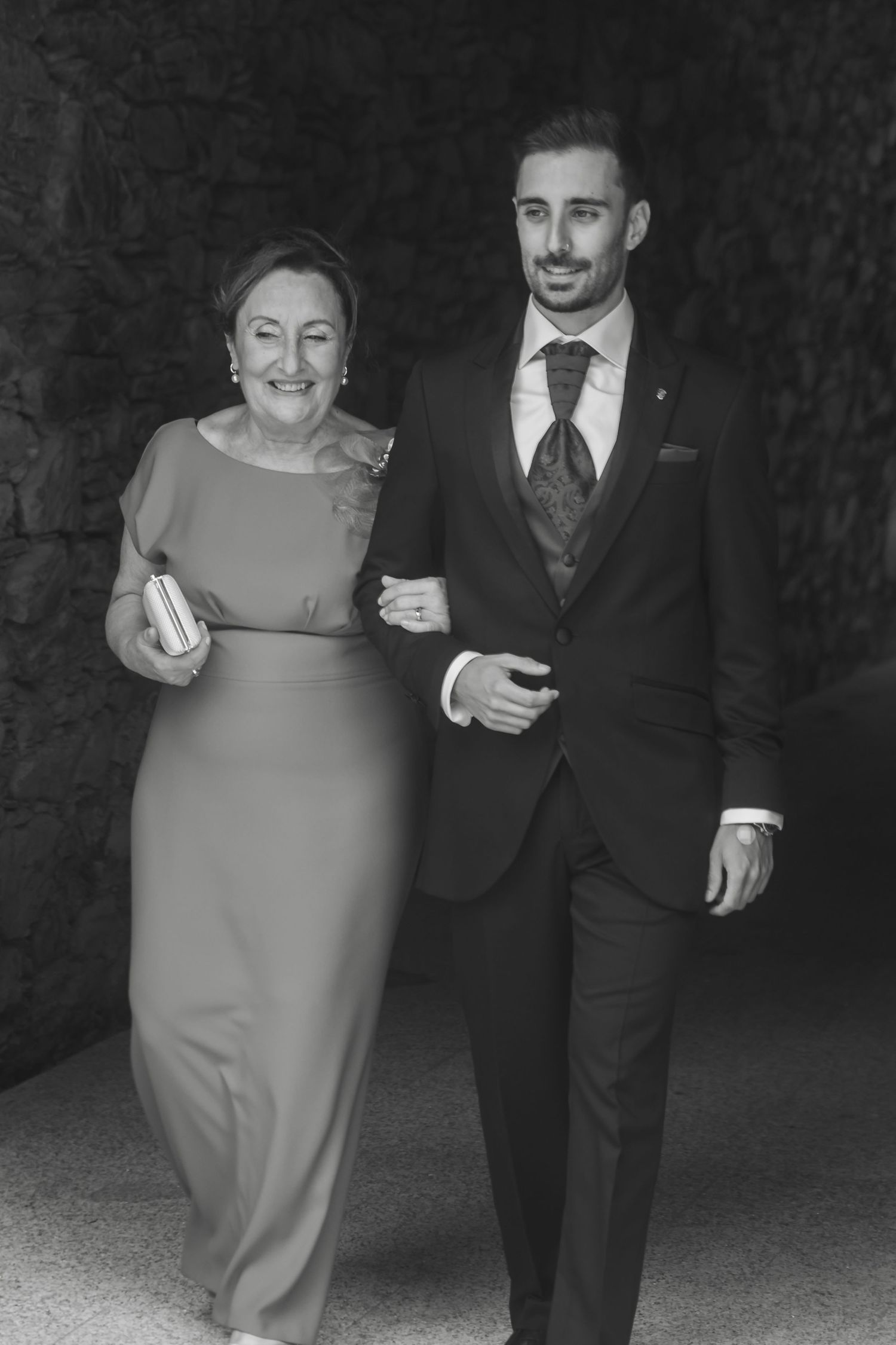 Elegant black and white photo of a formal occasion with two people walking arm in arm.